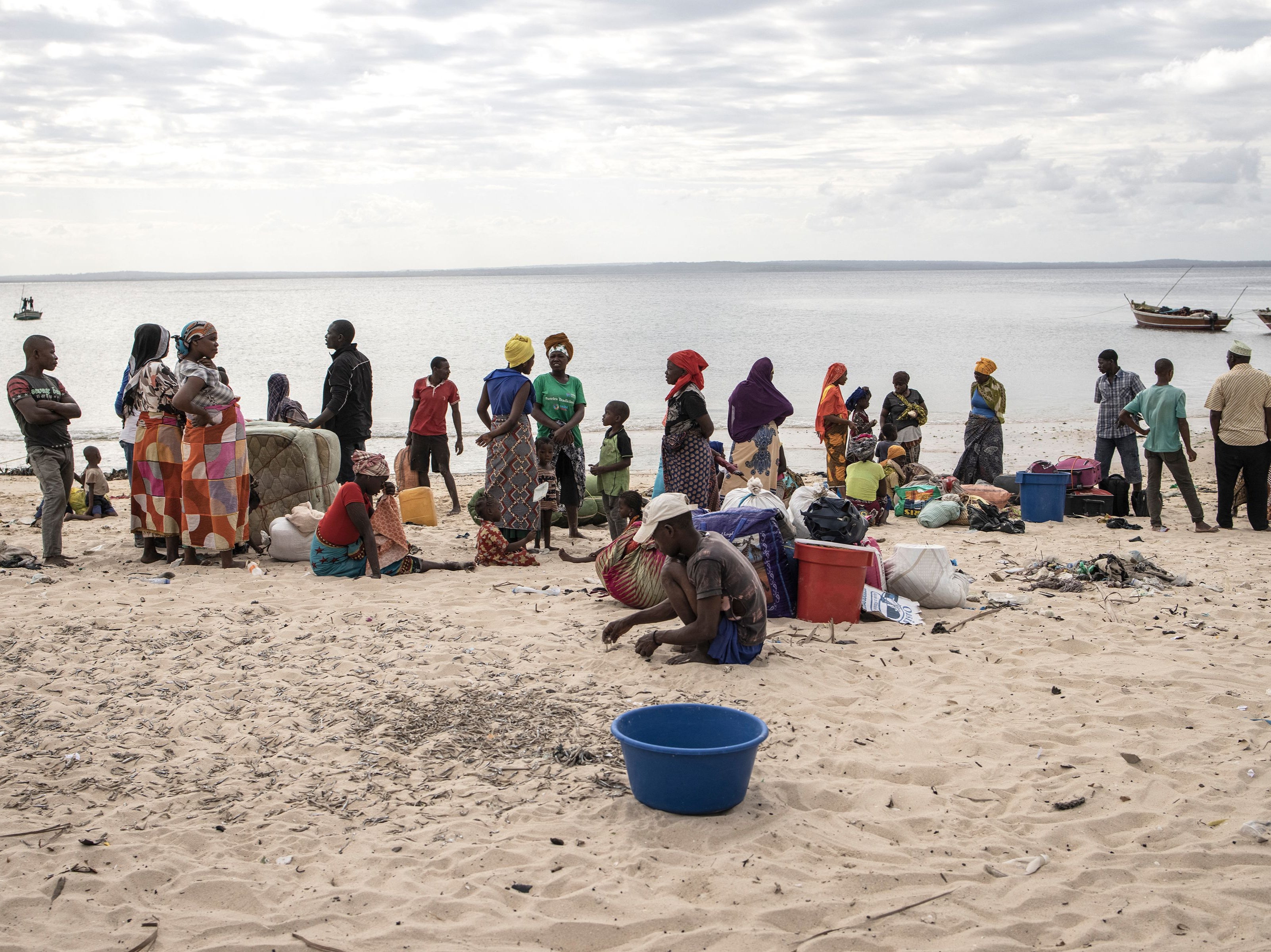 People gather with their belongings as they arrive at Paquitequete beach in Pemba on 22 May 2021 after fleeing Palma by boat