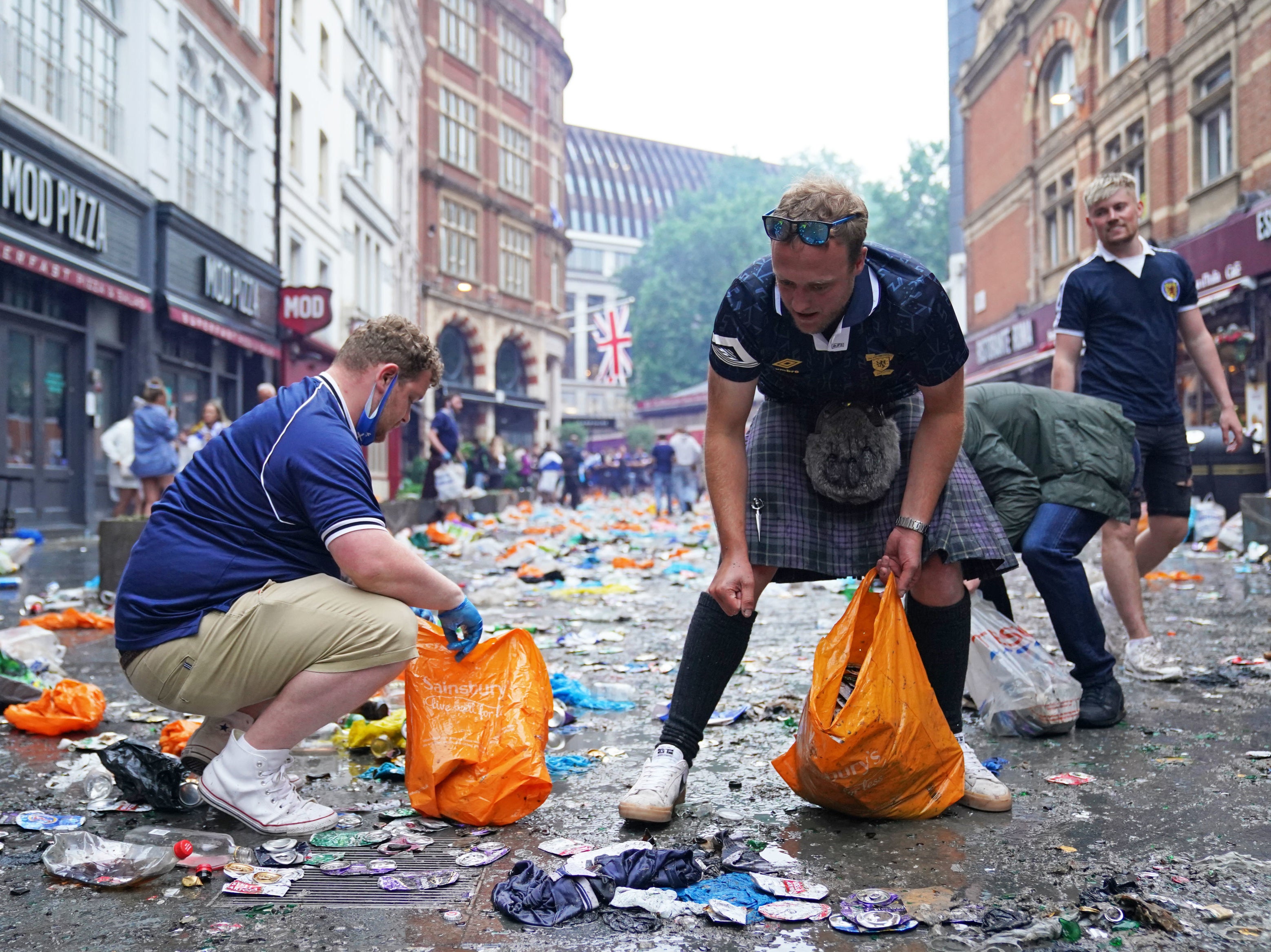 Scotland fans clean up litter in Irving Street near Leicester Square, London.