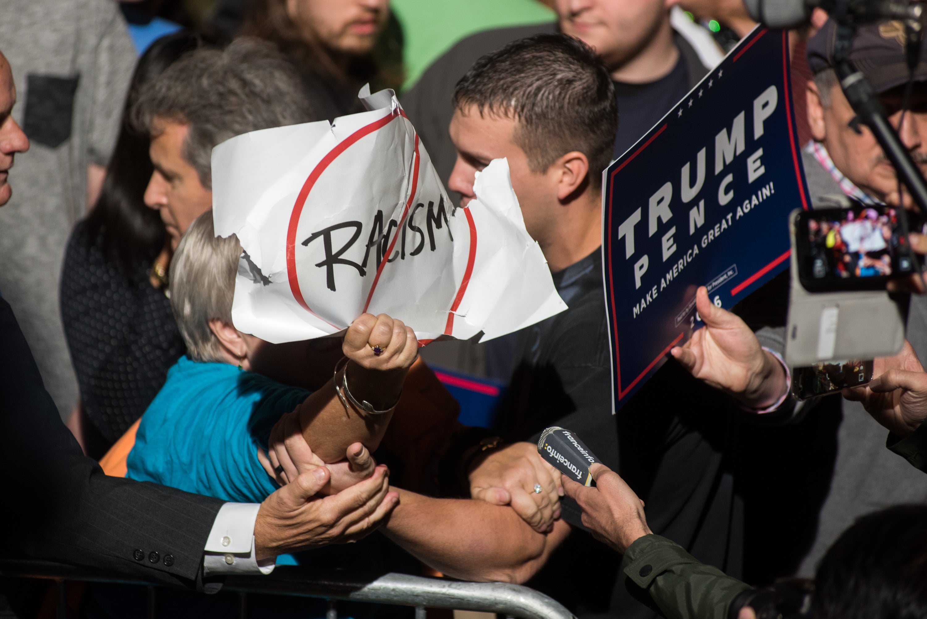 A protester with an anti-racism sign is confronted and removed from a rally for Republican Presidential candidate Donald J. Trump at the McGrath Amphitheater on October 28, 2016 in Cedar Rapids, Iowa. The state’s governor has signed a bill cracking down on crimes associated with protests