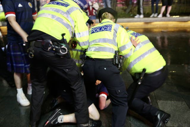 <p>Police officers take a fan into custody at Leicester Square after Scotland played to a goalless draw against rivals England</p>