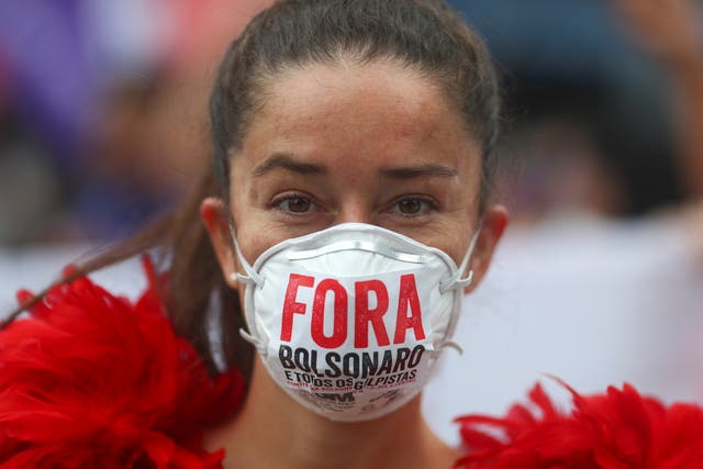 <p>‘Fora Bolsonaro’ (‘Bolsonaro out’): A woman protests against Brazil’s President Jair Bolsonaro’s handling of Covid-19 </p>