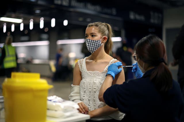 <p>A person receives a Covid vaccine at a mass vaccination centre at Tottenham Hotspur Stadium</p>