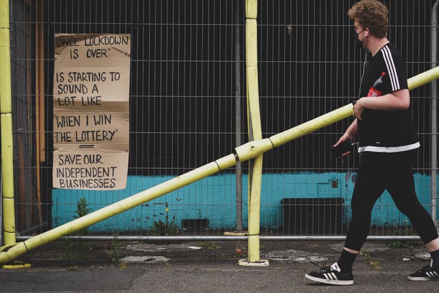 <p>A man walks past a poster referring to the end of lockdown like winning the lottery in the Totterdown area of Bristol</p>