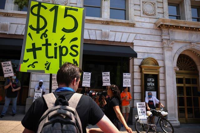 <p>An activist holds a sign up outside Old Ebbitt Grill restaurant during a “Wage Strike” demonstration on May 26th, 2021 in Washington, DC. Delaware lawmakers have voted to give final approval to raising the state’s minimum wage to $15 an hour.</p>
