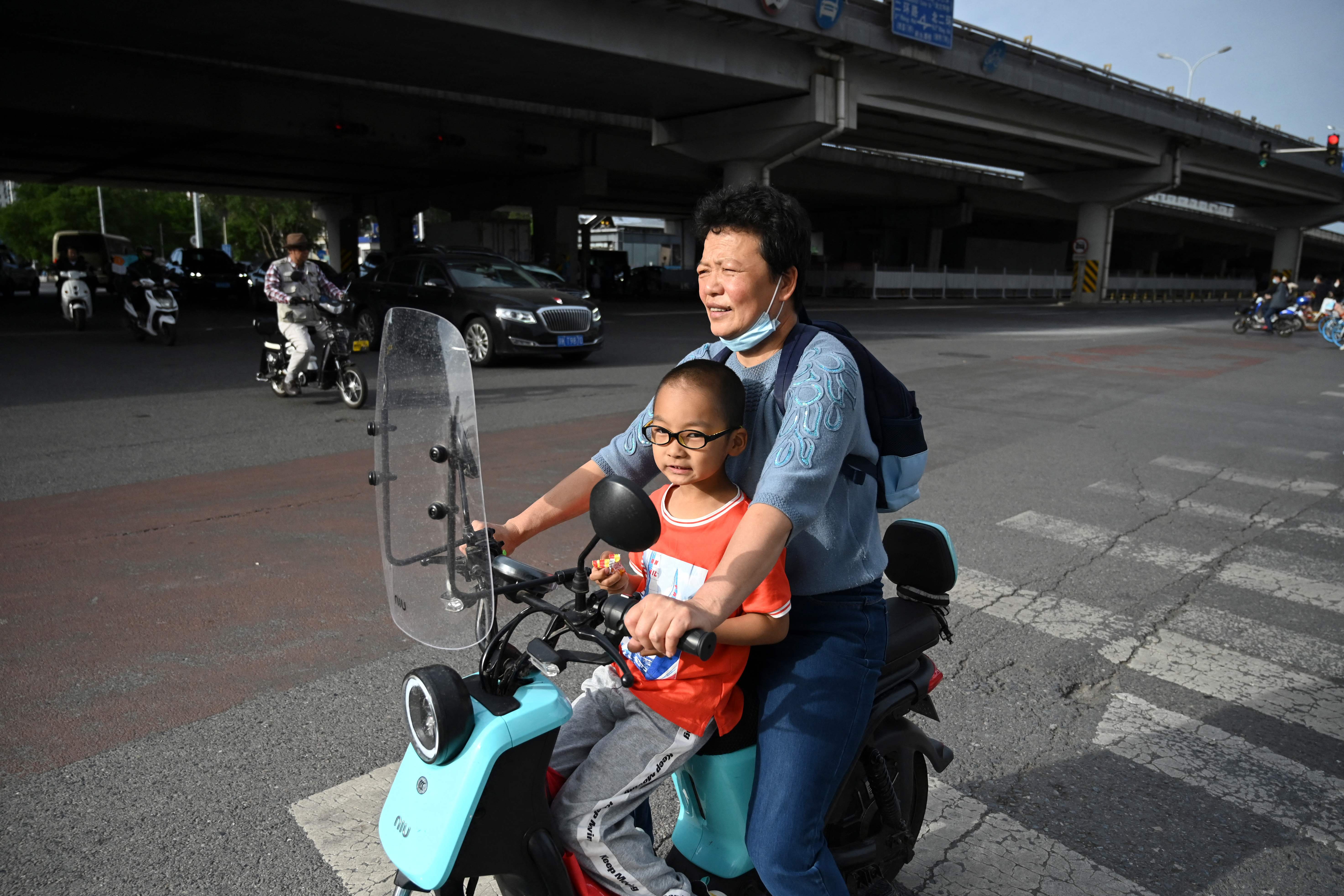 File: A woman carries a child on her electric bike in Beijing on 2 June, 2021