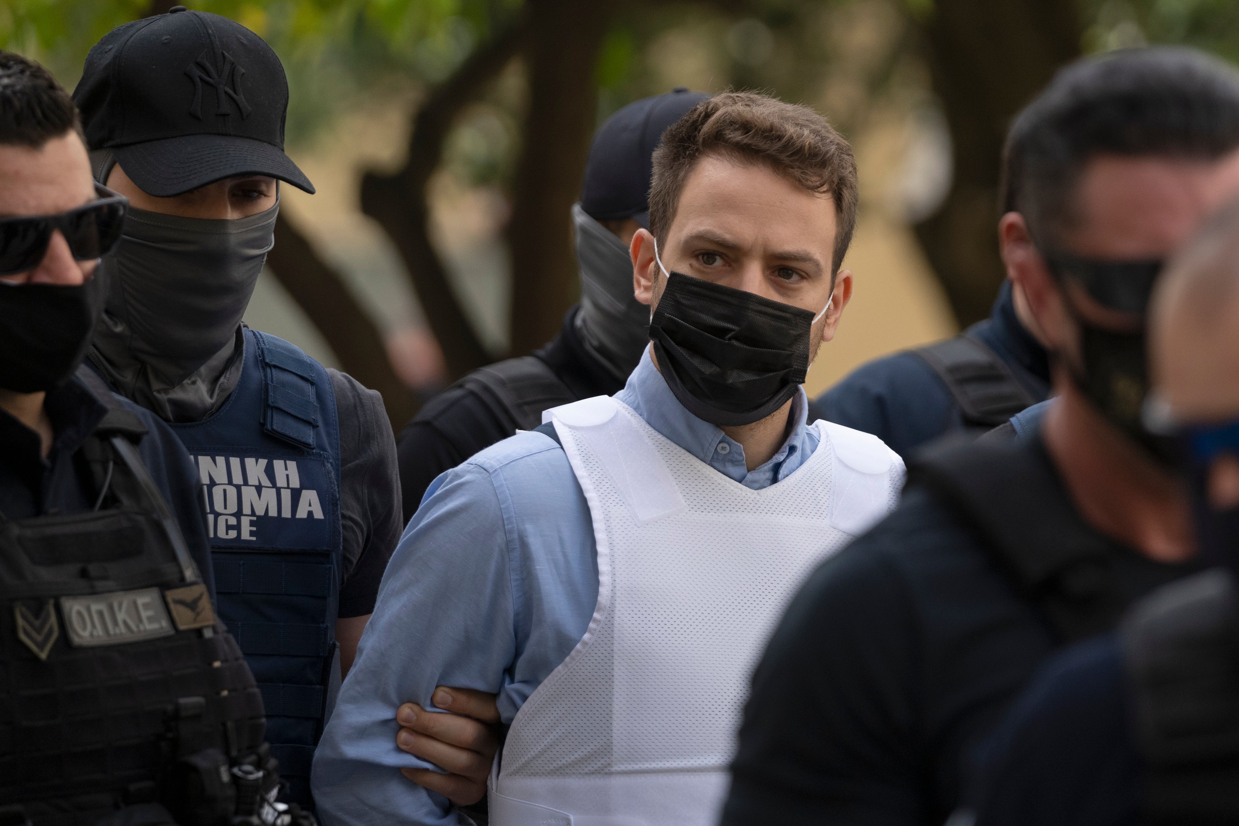 Helicopter pilot Babis Anagnostopoulos, center, escorted by police officers arrives in court