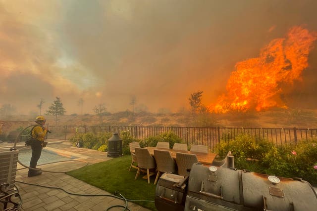 <p>A firefighter prepares to battle the North Fire from a backyard on Via Patina, in Santa Clarita, California earlier this year</p>