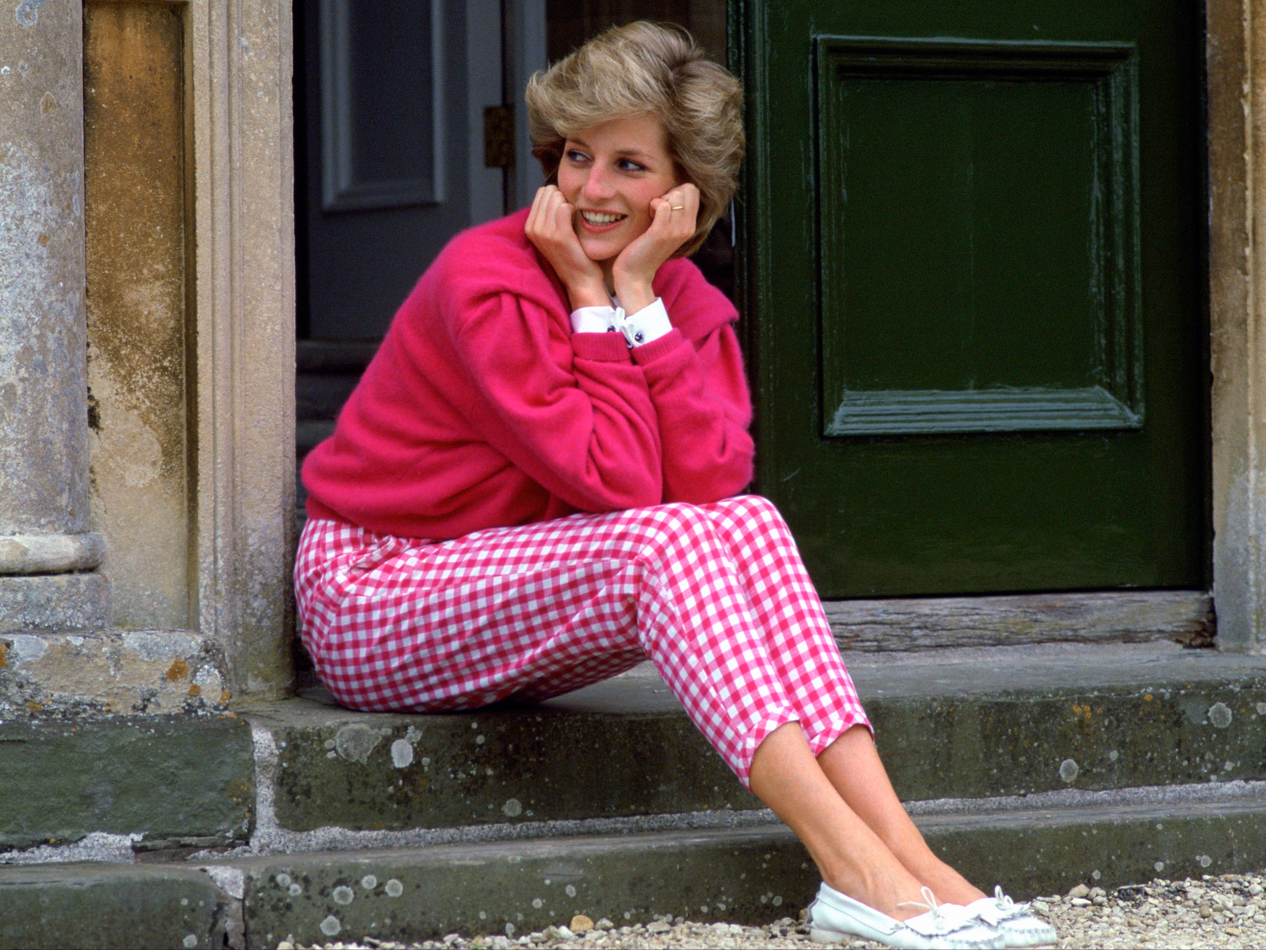 Princess Diana pictured outside her countryside home, Highgrove, in 1986. One of her most iconic looks, Diana chose a pair of high-waisted gingham pink trousers and an oversized fuchsia jumper with a white shirt underneath. The look was recreated in series four of The Crown .