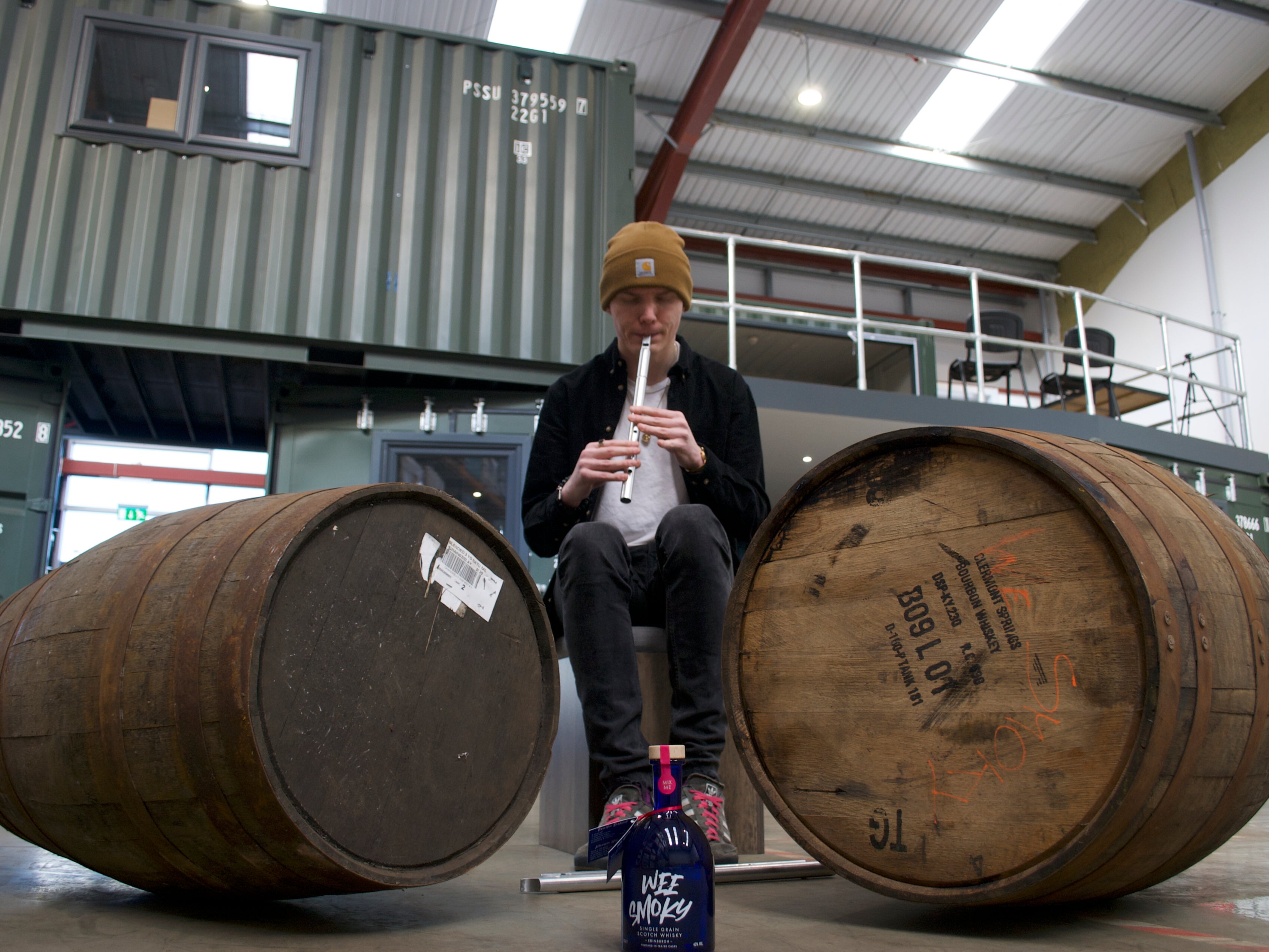 <p>Ali Levack plays the tin whistle to casks of whisky</p>