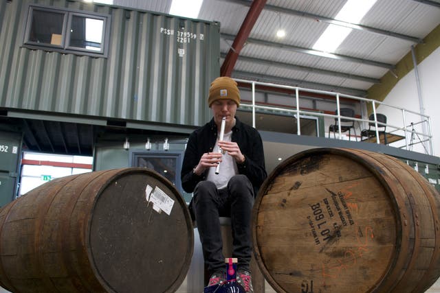 <p>Ali Levack plays the tin whistle to casks of whisky</p>