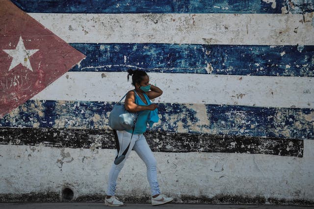 <p>A woman walks near a wall depicting the Cuban flag in Havana as the UN meets in New York</p>