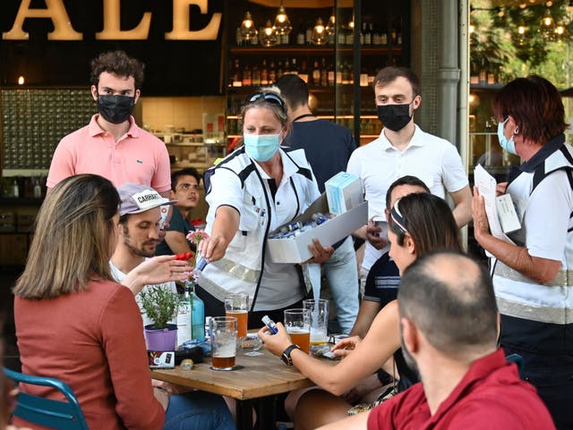 <p>Mediadores anti-Covid entregan desinfectante de manos a los clientes en la terraza de un bar en Estrasburgo</p>