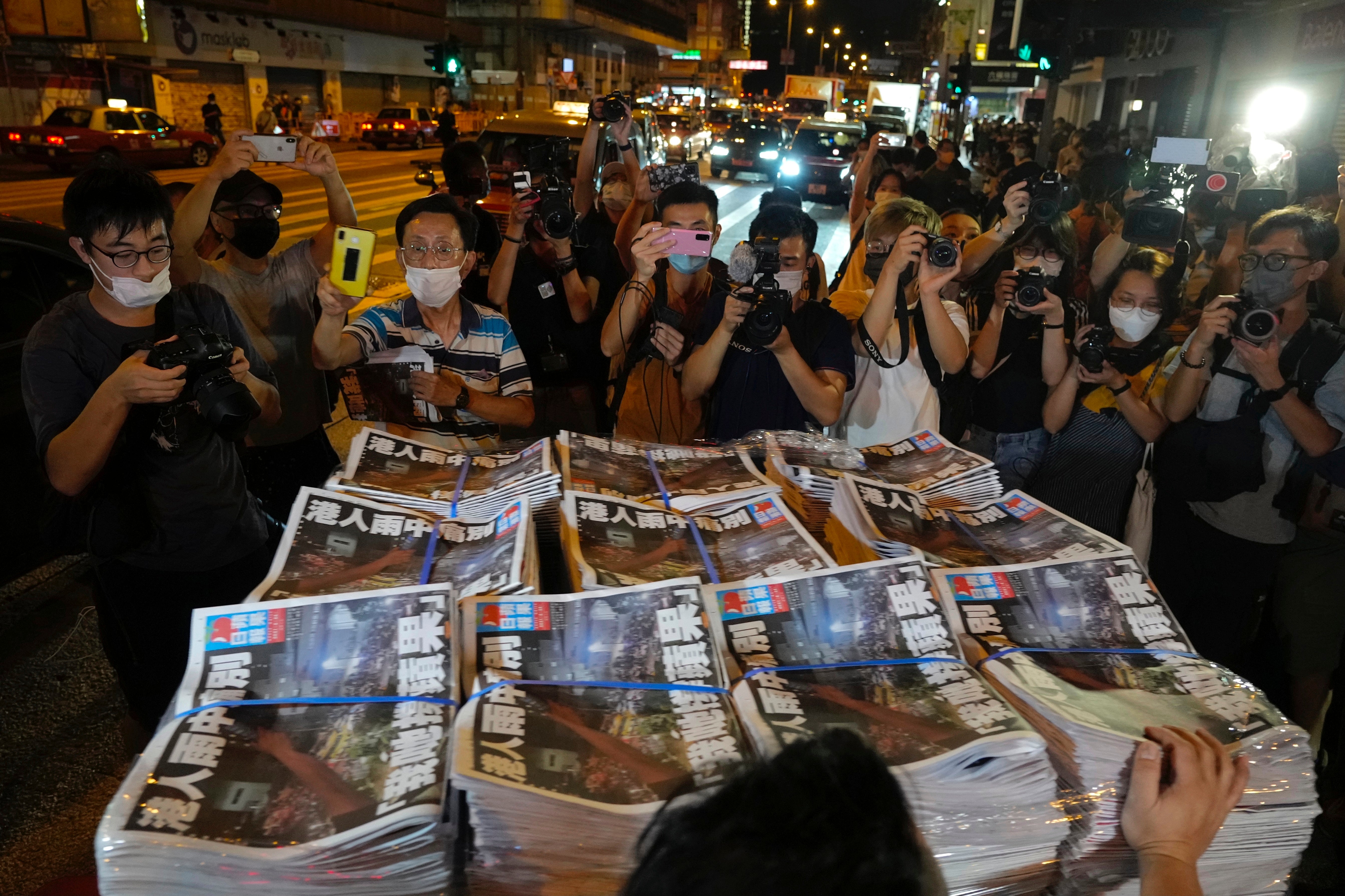 People gather to buy the last issue of Apple Daily as it arrives at a newspaper booth in Hong Kong, early Thursday