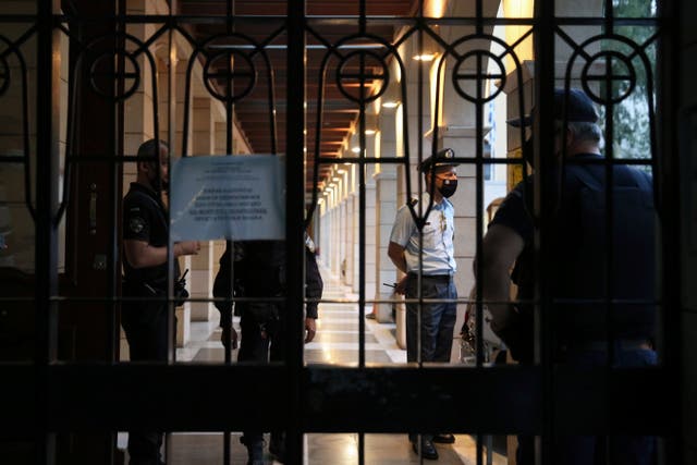 <p>Security guards at the gate of the Petraki Monastery in Athens, where a priest threw acid at bishops earlier this week</p>