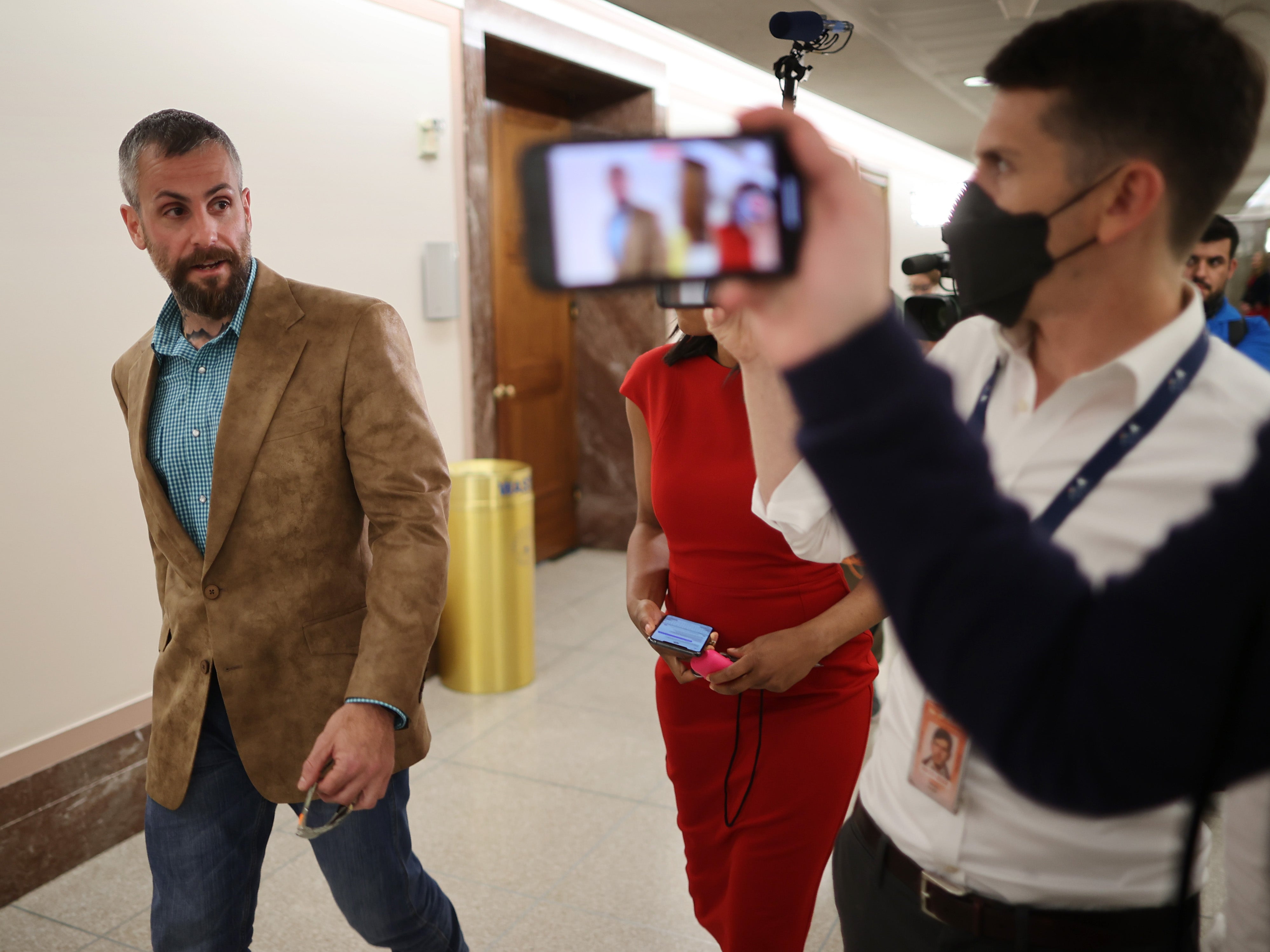 DC Metropolitan Police Officer Michael Fanone (left) is followed by reporters as he heads to a meeting with Sen Susan Collins.