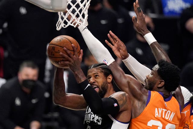 Los Angeles Clippers guard Paul George, left, shoots as Phoenix Suns centre Deandre Ayton defends