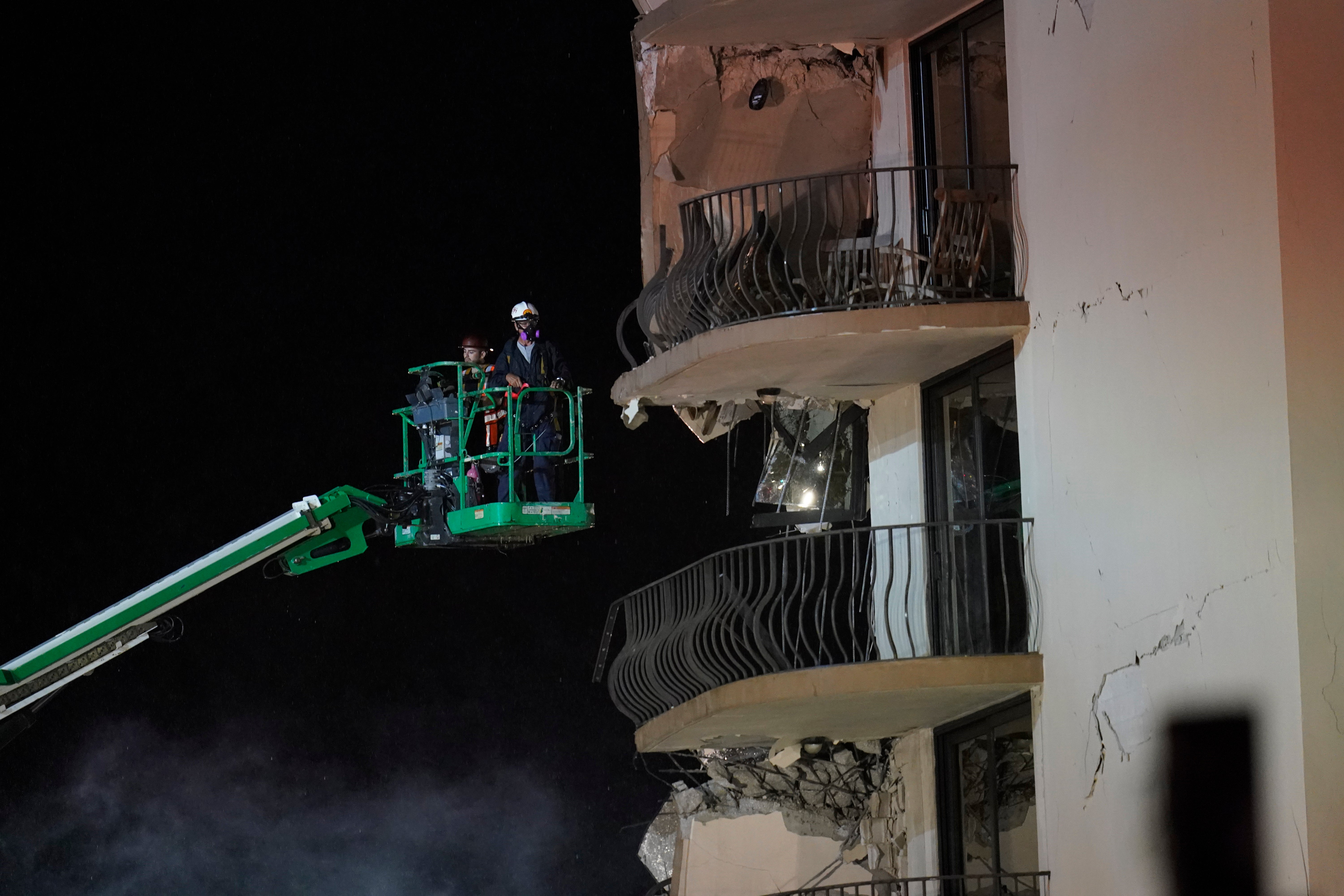 Workers use a lift to investigate balconies in the still-standing portion of the building, as rescue efforts continue where a wing of a 12-story beachfront condo building collapsed