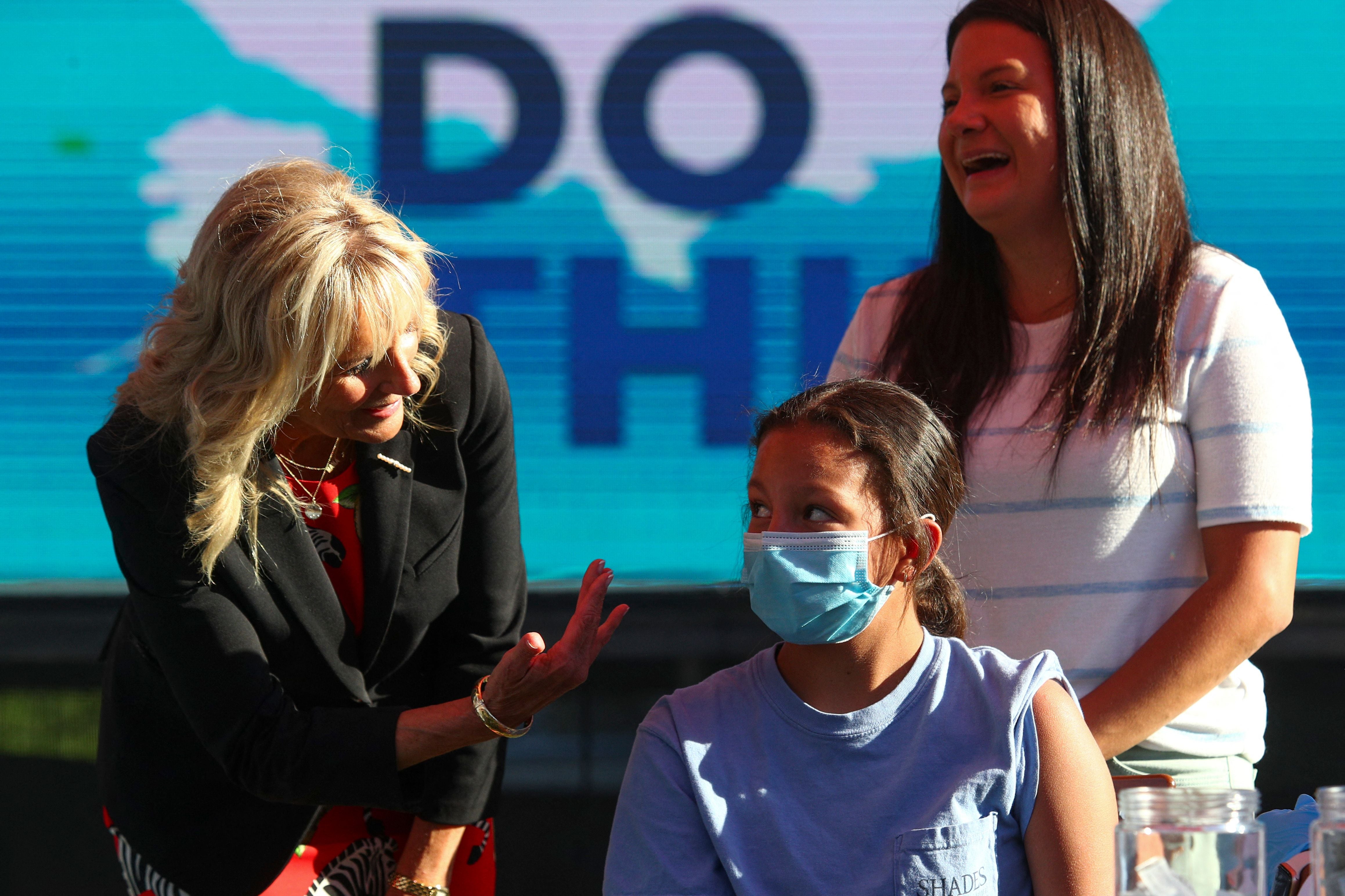 US first lady Jill Biden (L) speaks to Adriana Lyttle, 12, as she receives her vaccine at a Covid-19 vaccination