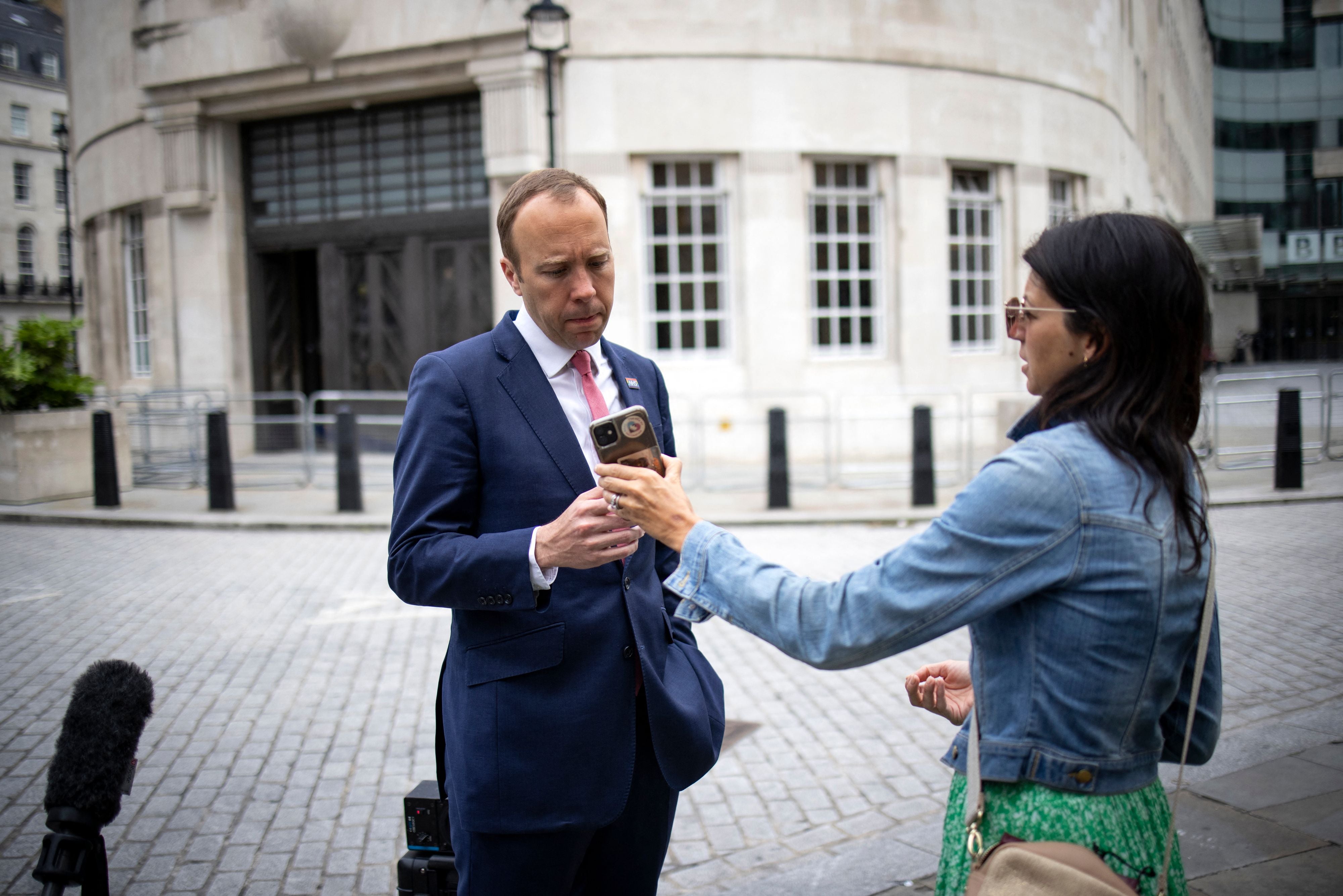 Matt Hancock looks at the phone of his aide Gina Coladangelo, who he was caught kissing on CCTV, as they leave the BBC earlier this month