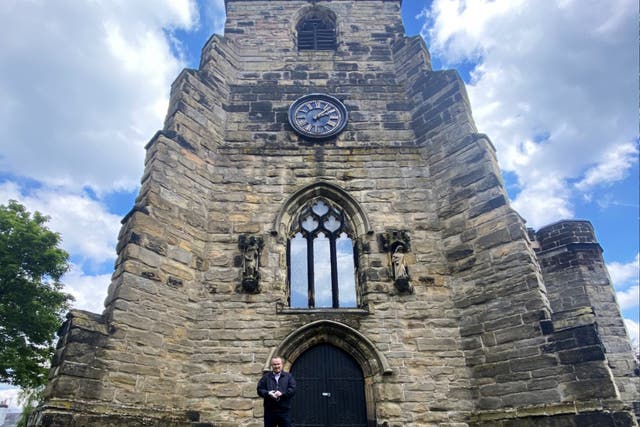 <p>Church treasurer and local historian Peter Beck outside the church clock tower</p>