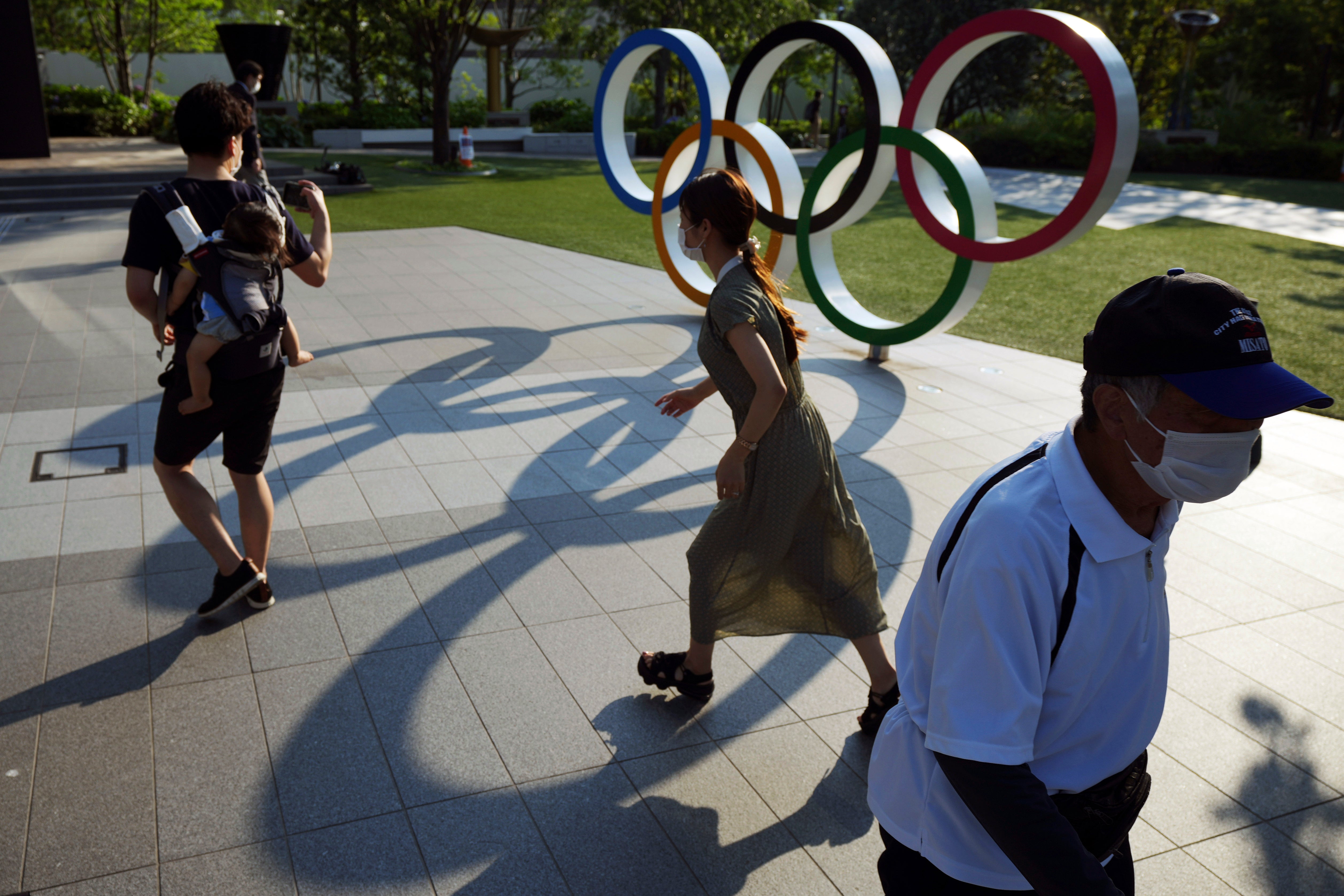People walking past the Olympic rings in Tokyo. The Japanese public has generally been opposed to the Games, partly over fears that coronavirus levels will spike as about 100,000 people enter the country