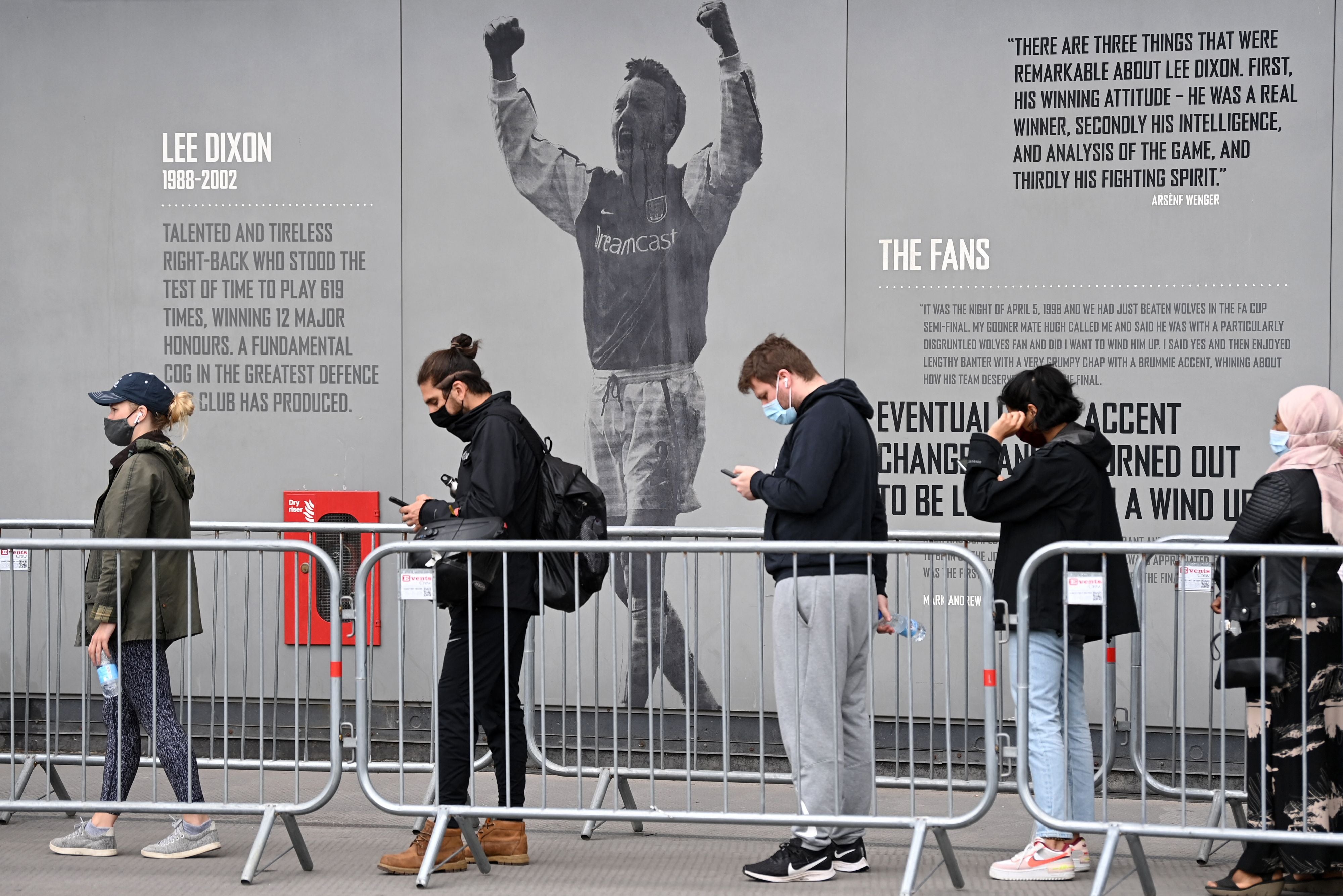 Members of the public queue to receive a dose of a Covid-19 vaccine outside a temporary vaccination centre set up a the Emirates Stadium, home to Arsenal football club, in north London on Friday