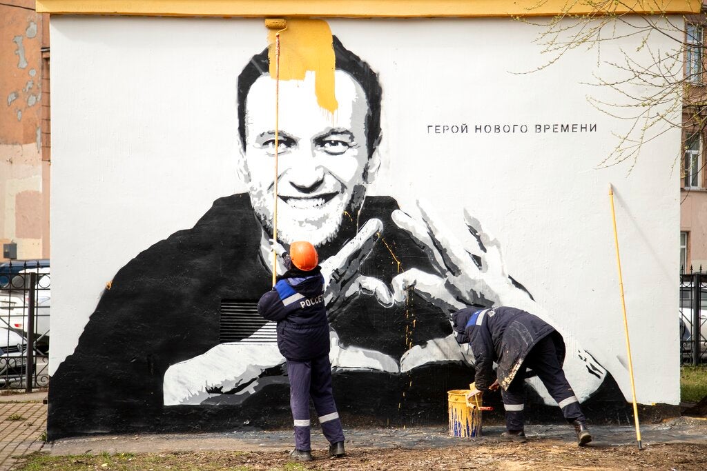 Workers paint over graffiti of Alexei Navalny in St. Petersburg in April. The words on the wall reading "Hero of our time"