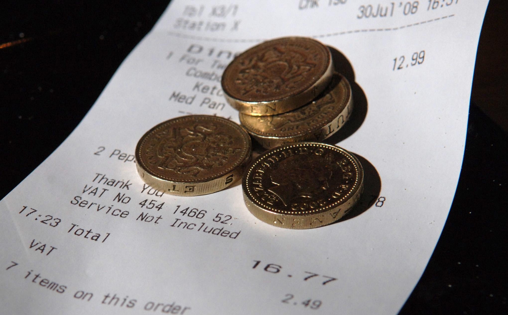 <p>Pound coins on top of a restaurant bill</p>
