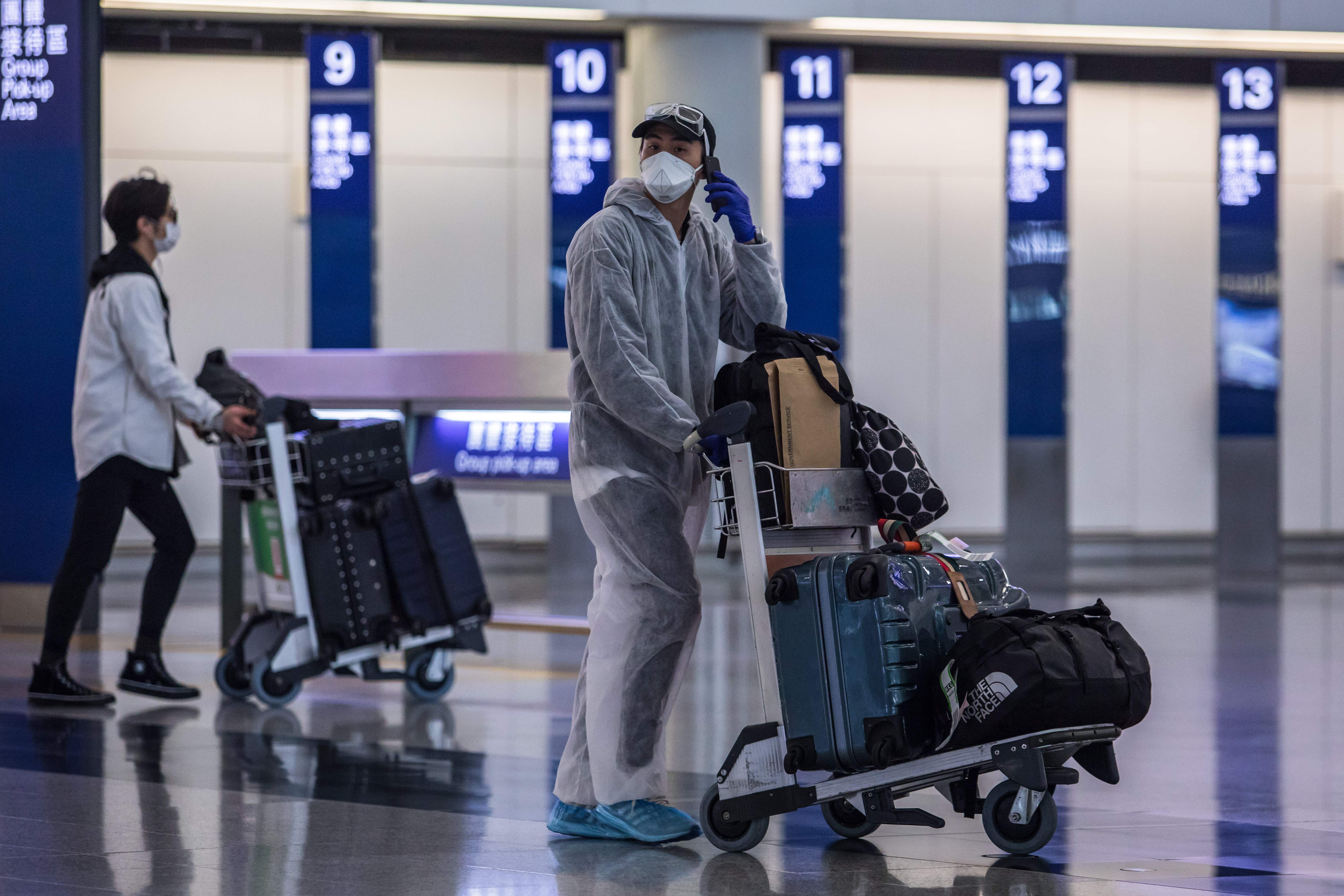 File: A passenger wearing a face mask and protective suit at the Hong Kong International Airport on 4 April, 2020