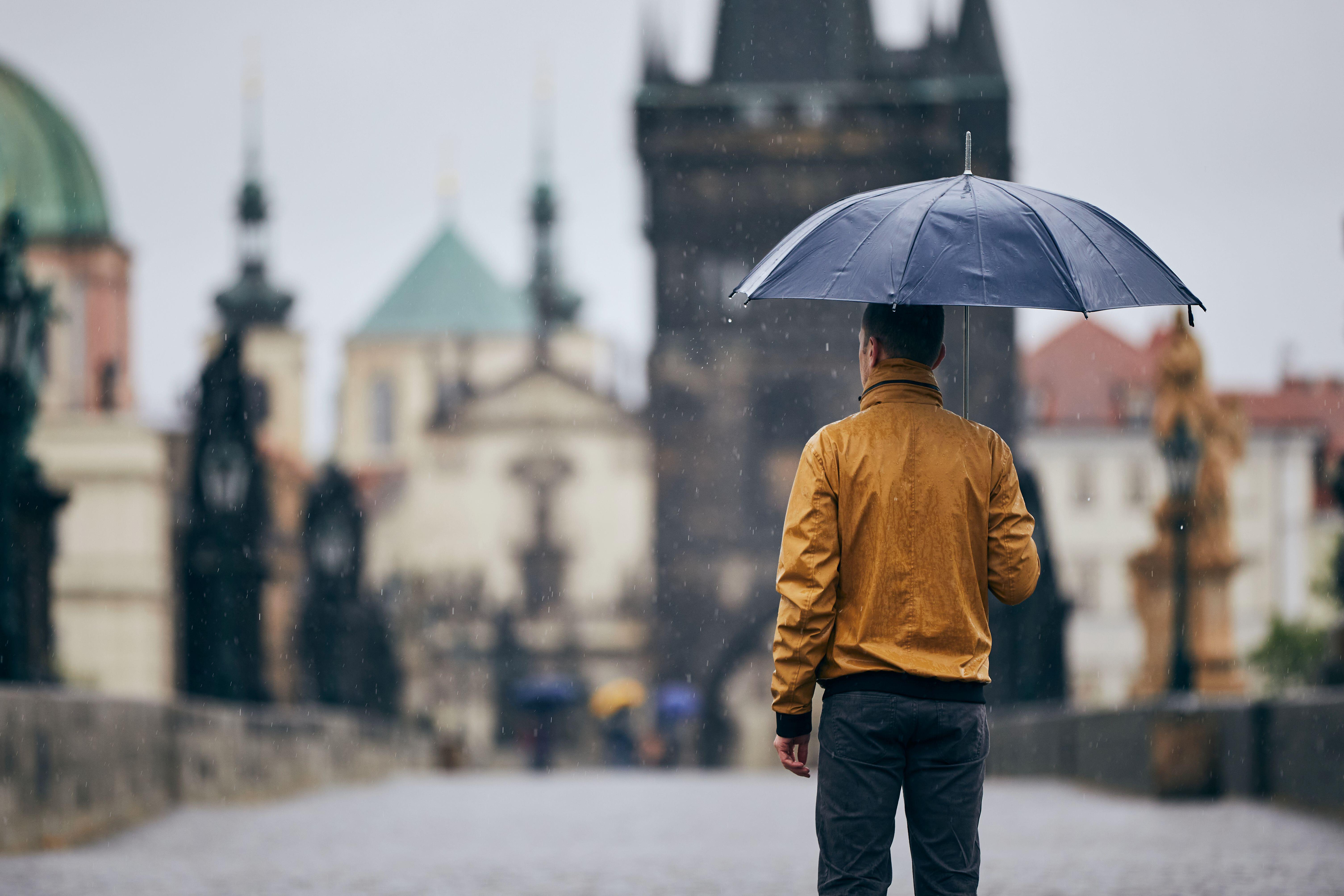 man standing with umbrella in the rain