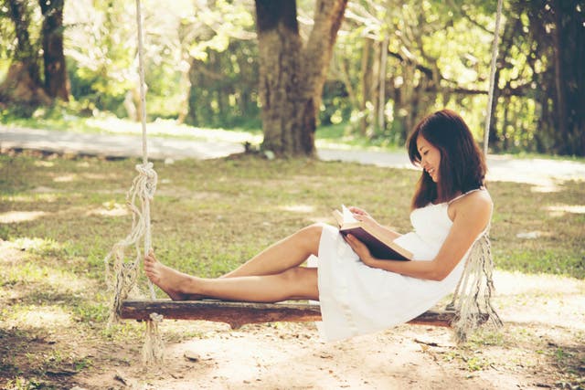 Woman sitting on a swing reading a book
