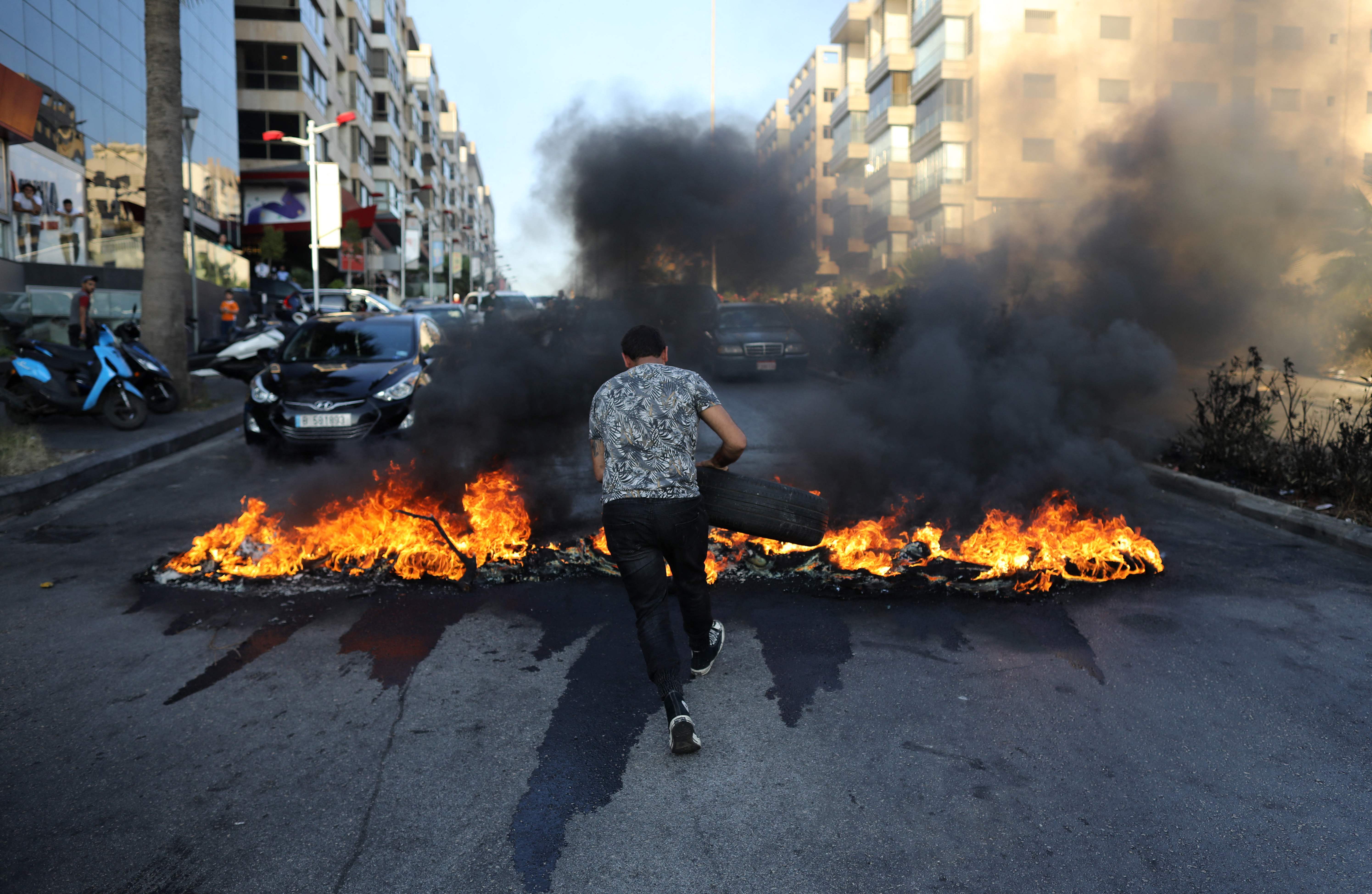 A Lebanese man sets tires on fire during ongoing protests against fuel and energy shortages in Beirut