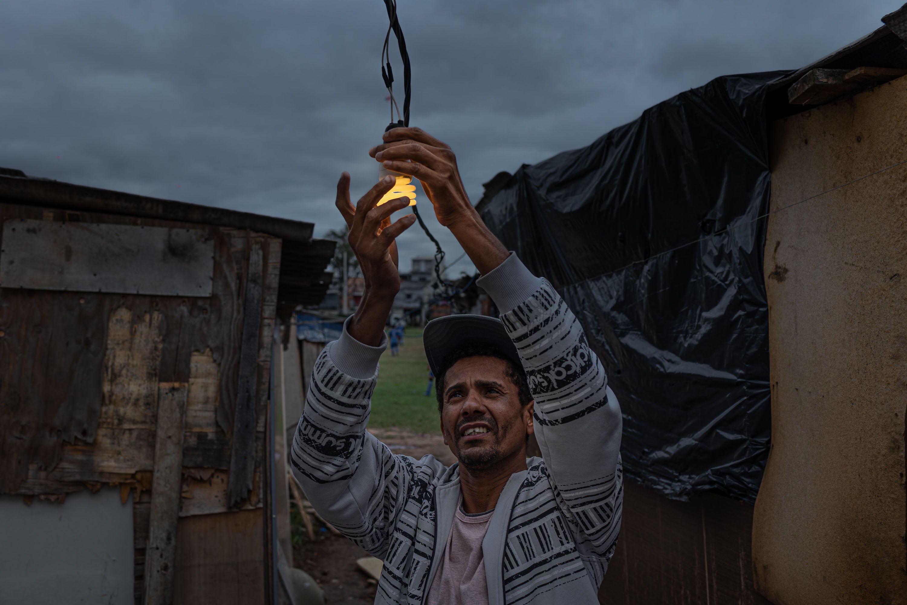 Fixing a lightbulb in the Jardim Julieta encampment