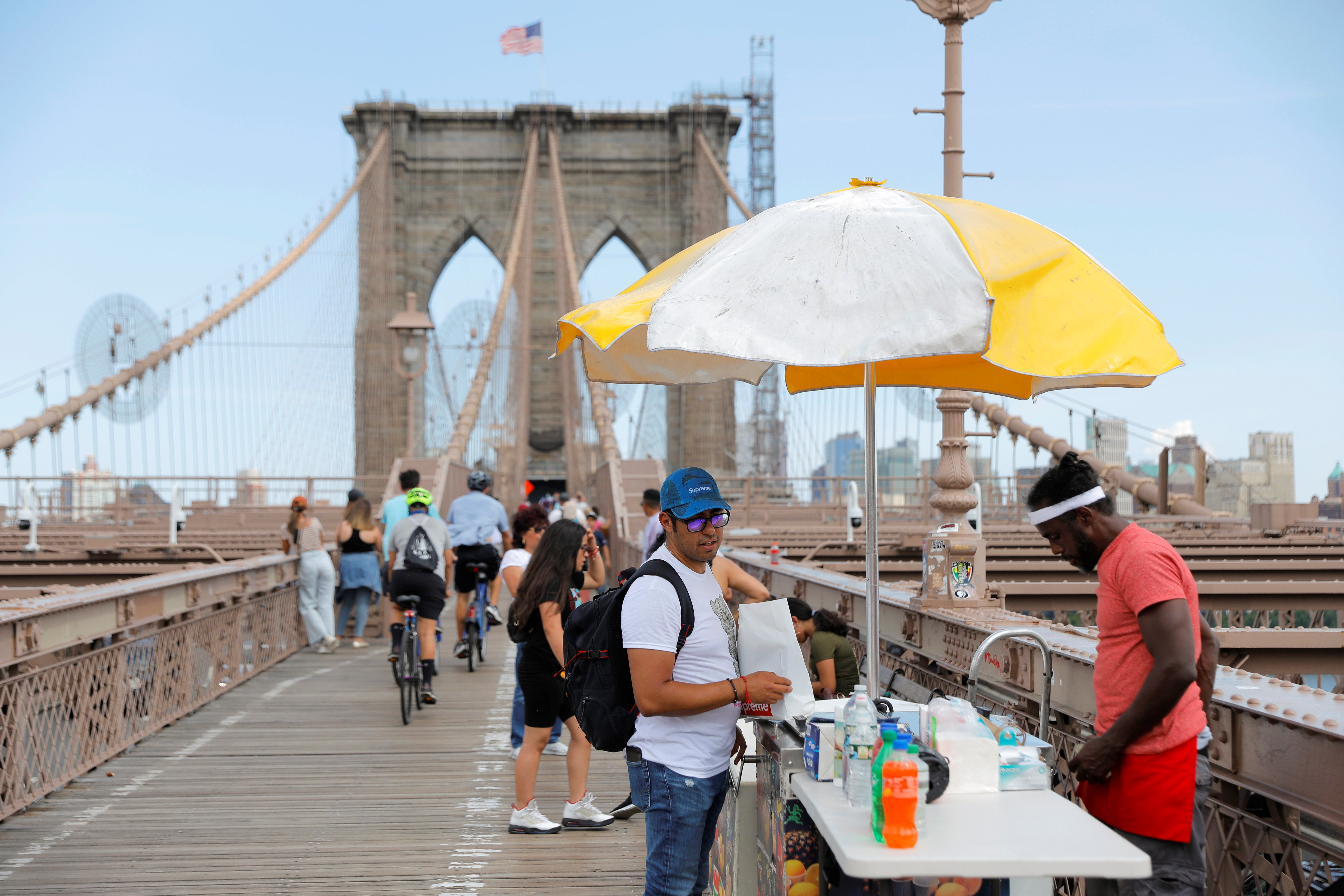 A person buys a drink on Brooklyn Bridge as New York swelters