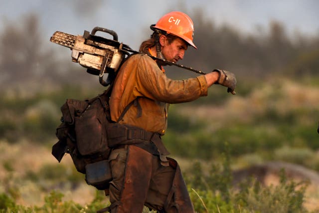 <p>A member of the U.S. Forest Service’s Trinity Hotshots firefighting crew carries a chain saw while hiking out of the burn zone Monday, June 28, 2021, at the Lava Fire north of Weed, Calif.</p>