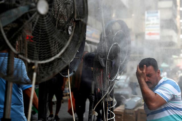 <p>A man stands by fans spraying water vapour deployed by donors to cool down pedestrians in Iraq’s capital Baghdad </p>