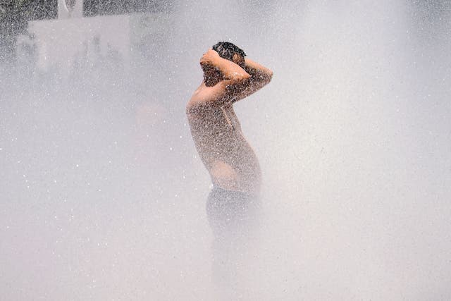 <p>A man cools off in a street fountain in Portland, Oregon</p>