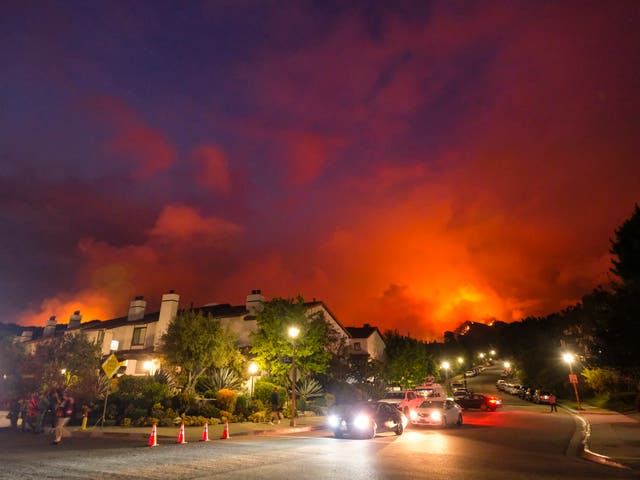 <p>Smoke rises behind homes in Pacific Palisades last month</p>