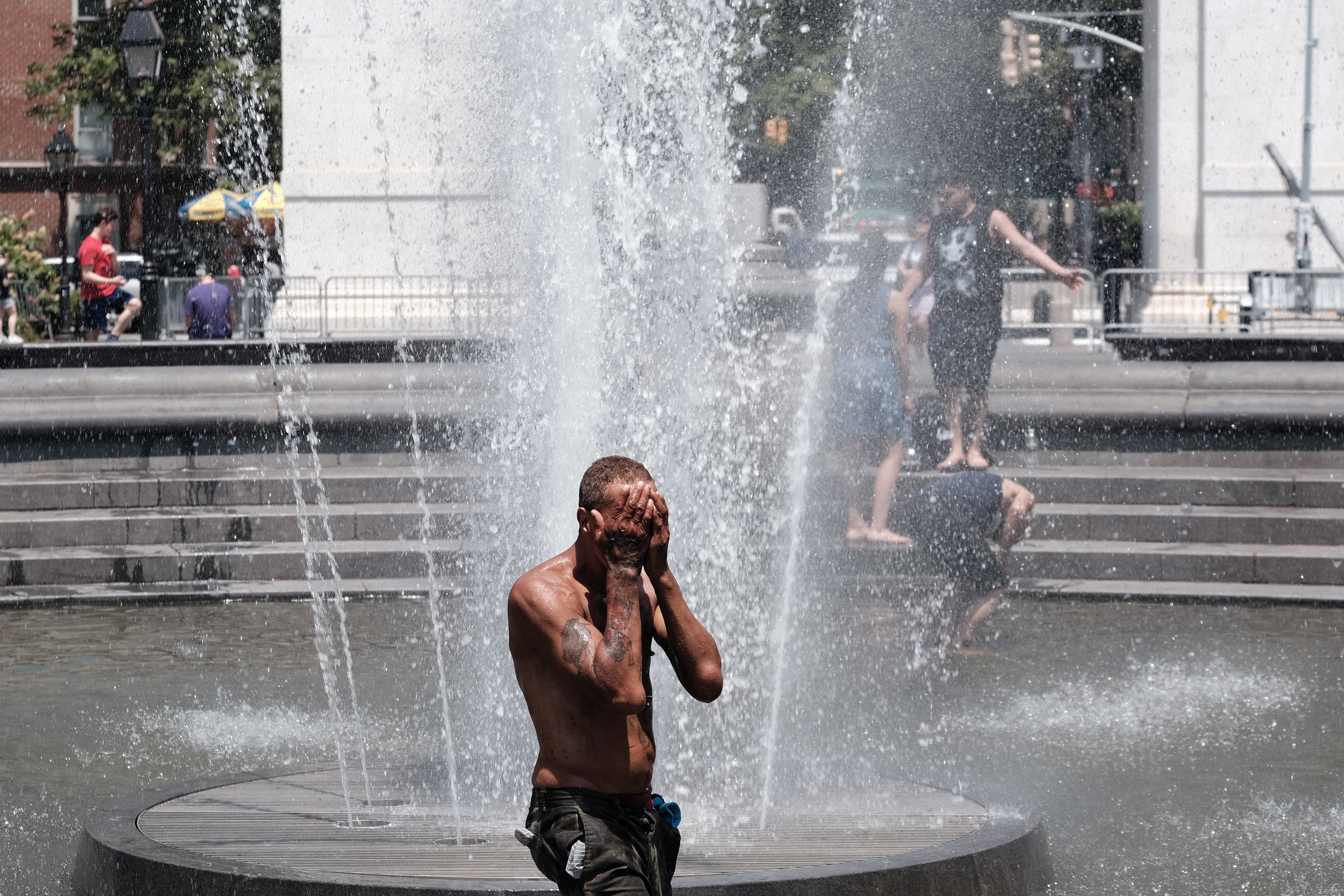New Yorkers cool off in Washington Square Park on 30 June as temperatures approach 100 degrees Fahrenheit during a bicoastal heat wave.