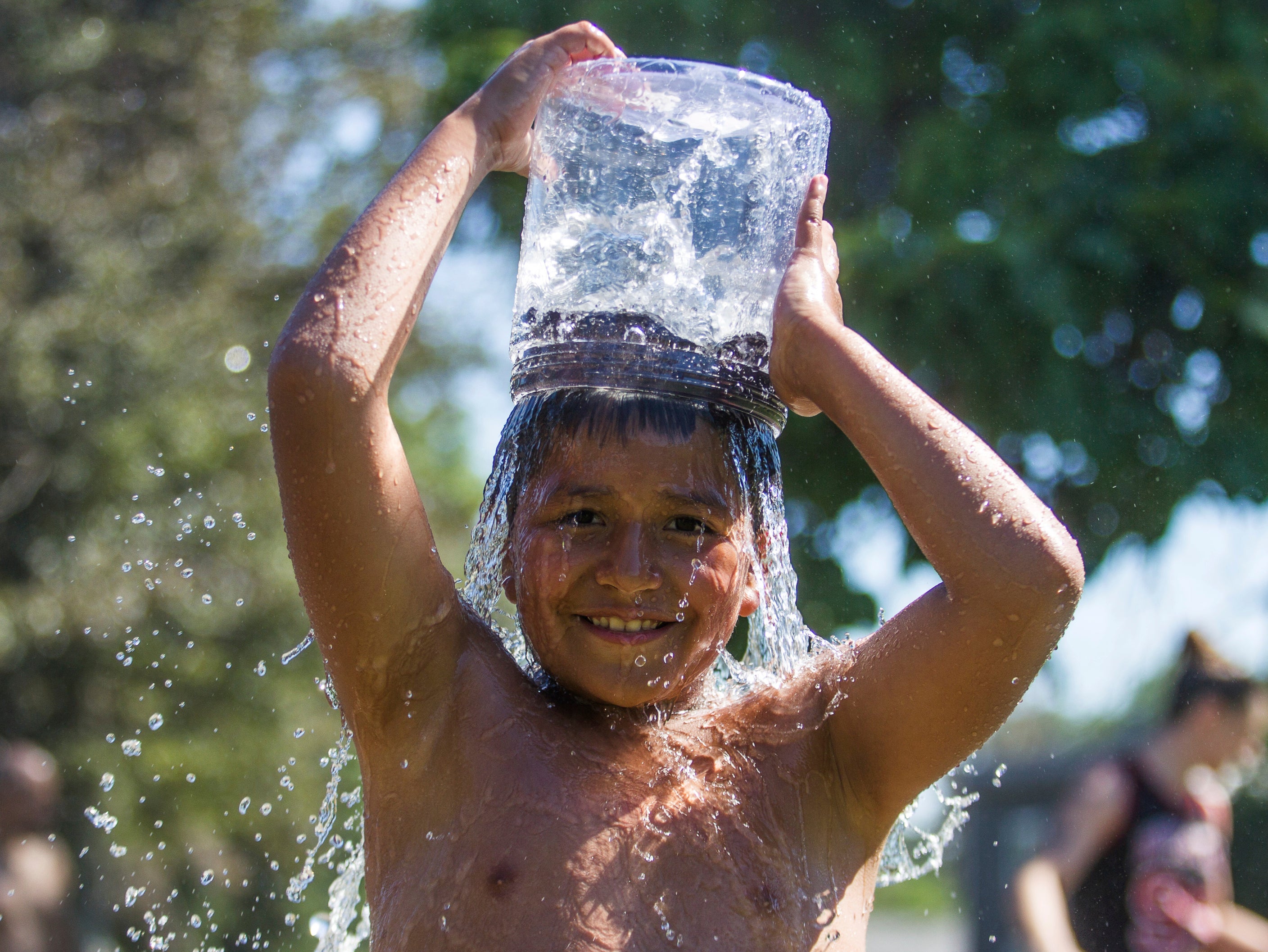 Pedro Valencia, 9, pours a bucket of water over his head