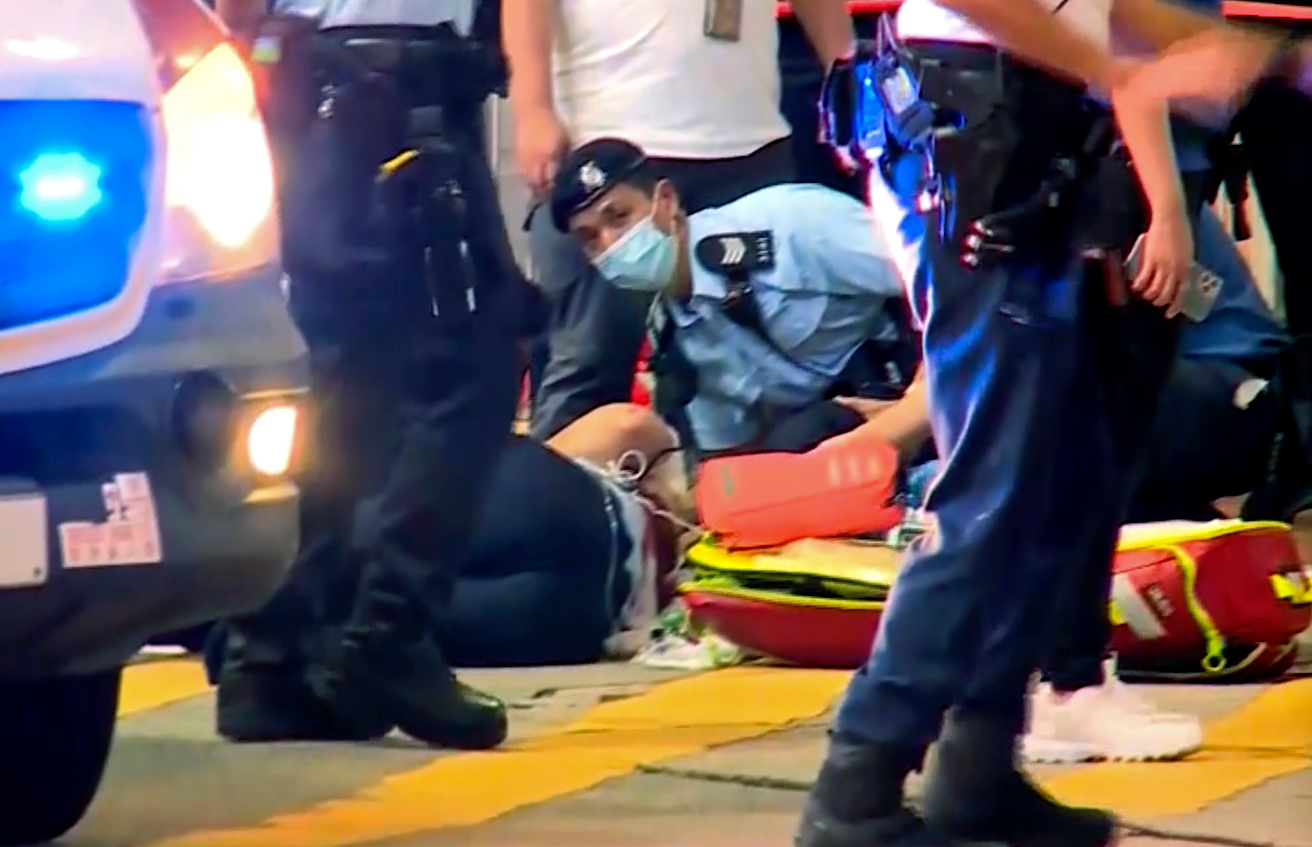 In this image from video provided by TVB, a police officer on the ground receives medical treatment after being stabbed by a man on a street in Causeway Bay of Hong Kong, 1 July 2021