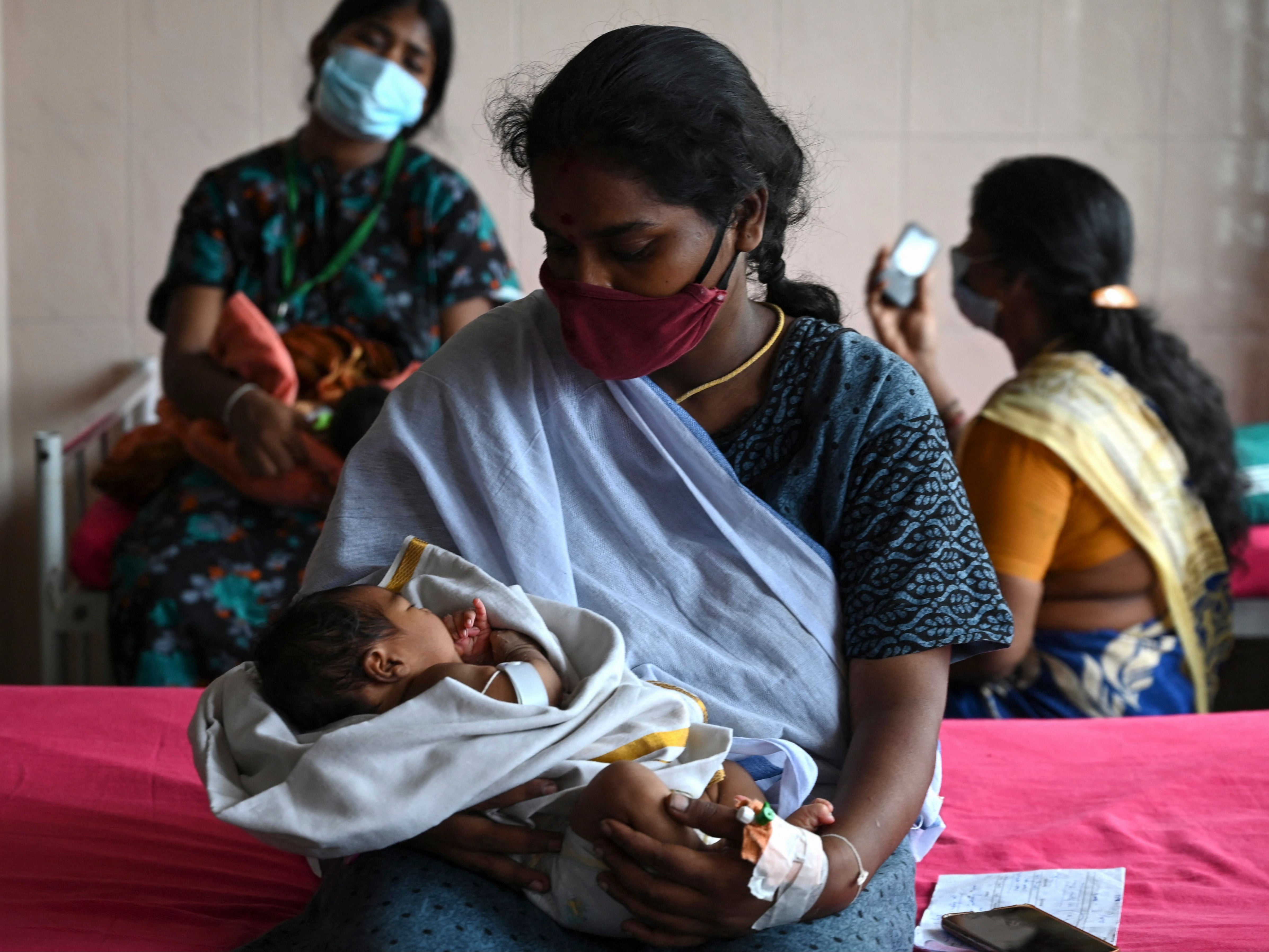 A mother, with her newborn baby, waits for a coronavirus vaccine at a government children hospital in Chennai