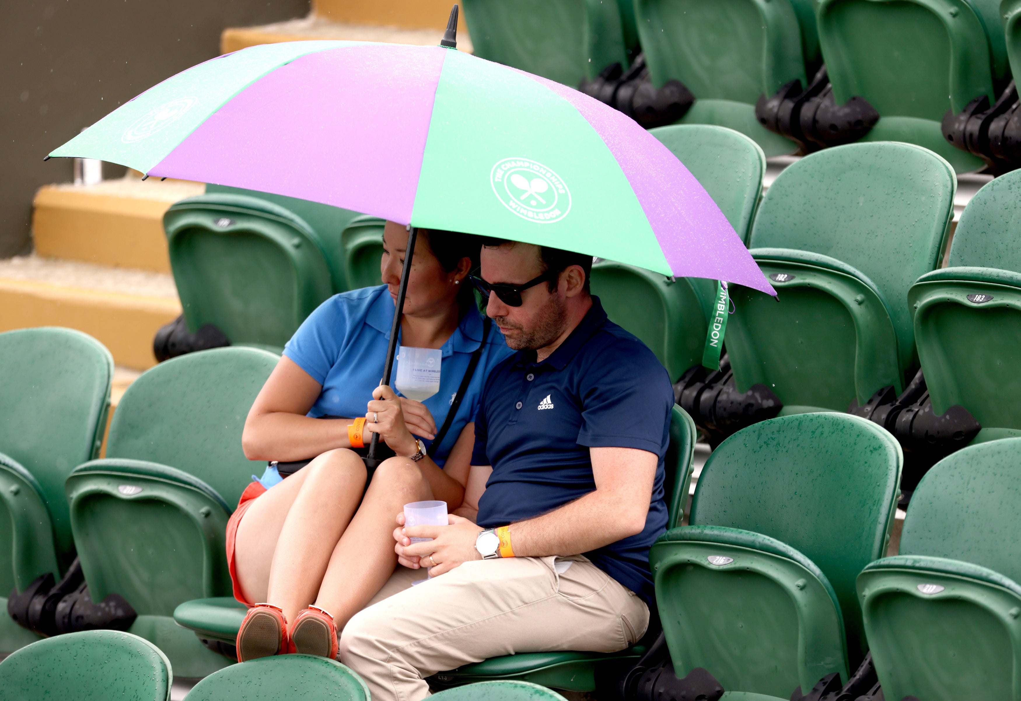 Spectators shelter from the rain as play is disrupted on day two of Wimbledon