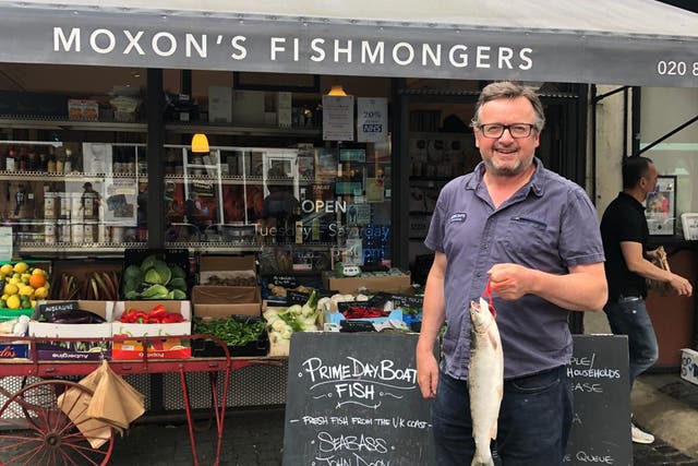<p>Robin Moxon stands outside one of his fishmongers advertising prime day boat fish</p>