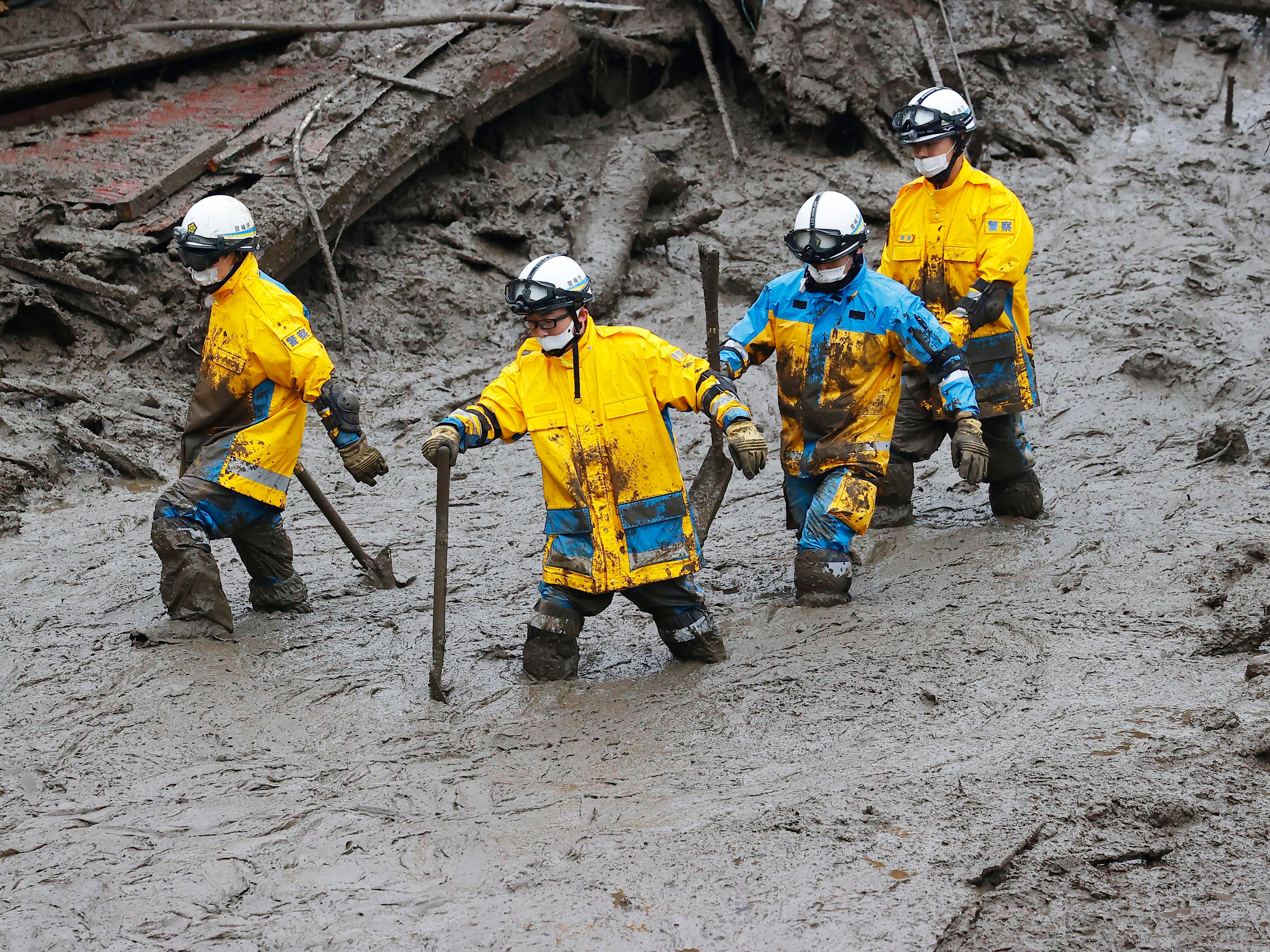 Rescuers wade through the mud in Atami, southwest of Tokyo