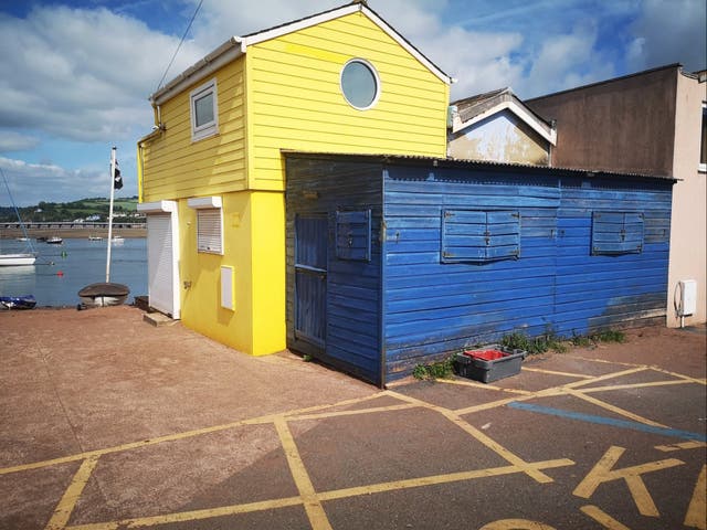 <p>A blue shed attached to a yellow beach hut in Teignmouth, Devon, is up for sale for offers over £45,000</p>