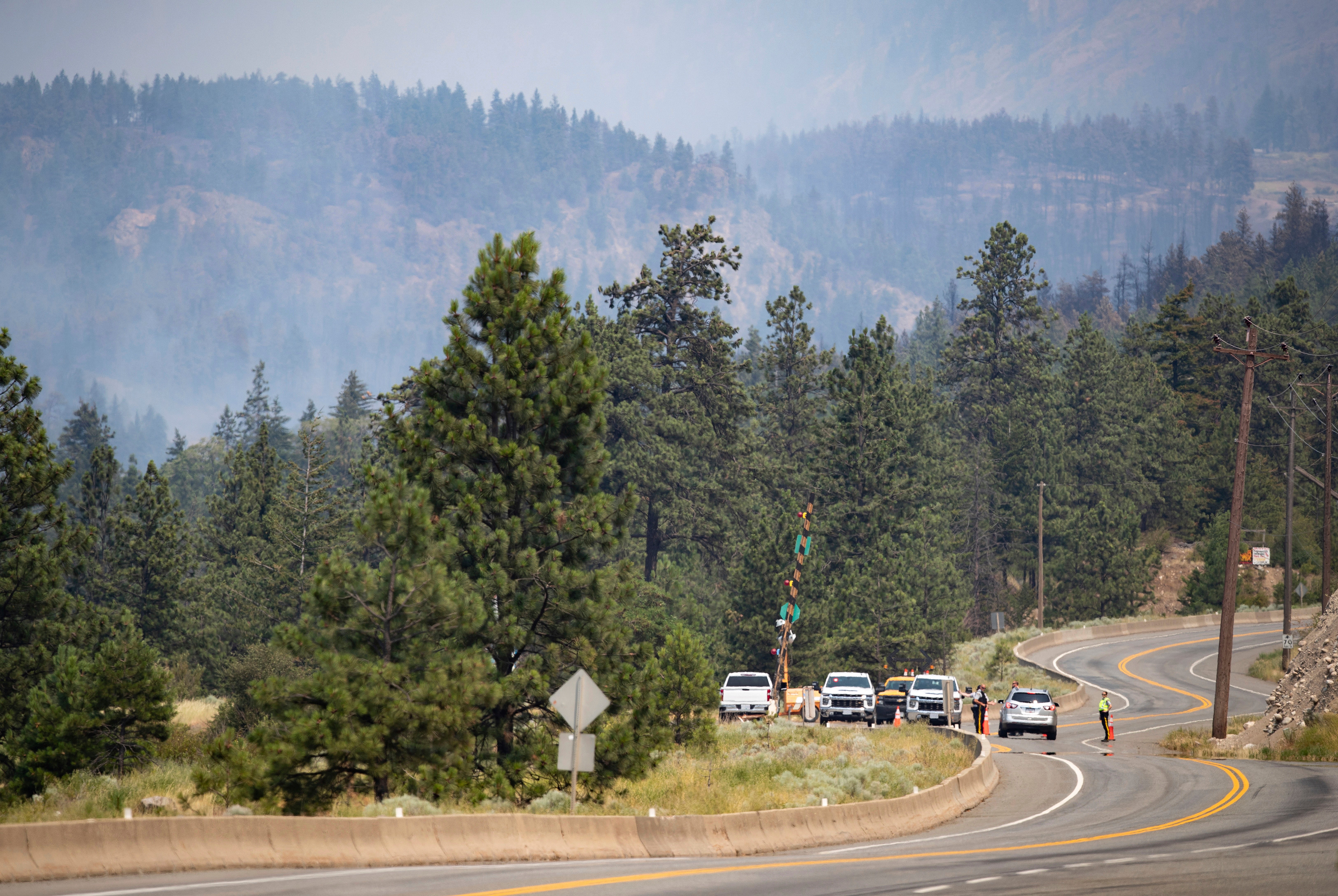 Royal Canadian Mounted Police (RCMP) officers man a roadblock on the Trans-Canada Highway as a wildfire burns in Lytton, British Columbia, Friday, July 2, 2021. Officials on Friday hunted for any missing residents of a British Columbia town destroyed by wildfire as Canadian Prime Minister Justin Trudeau offered federal assistance.