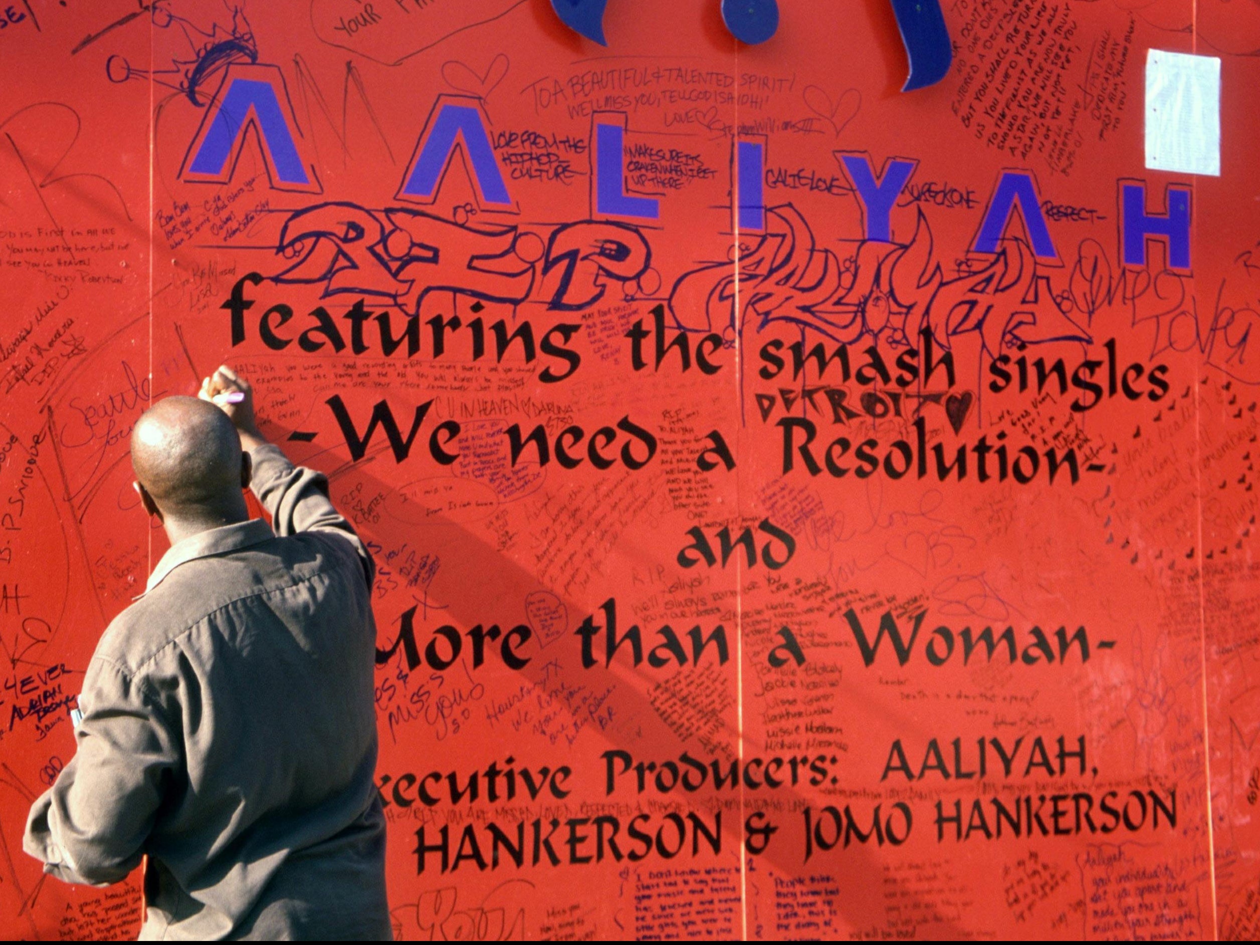 A fan writes on a tribute to Aaliyah on Sunset Boulevard after her funeral, 31 August 2001
