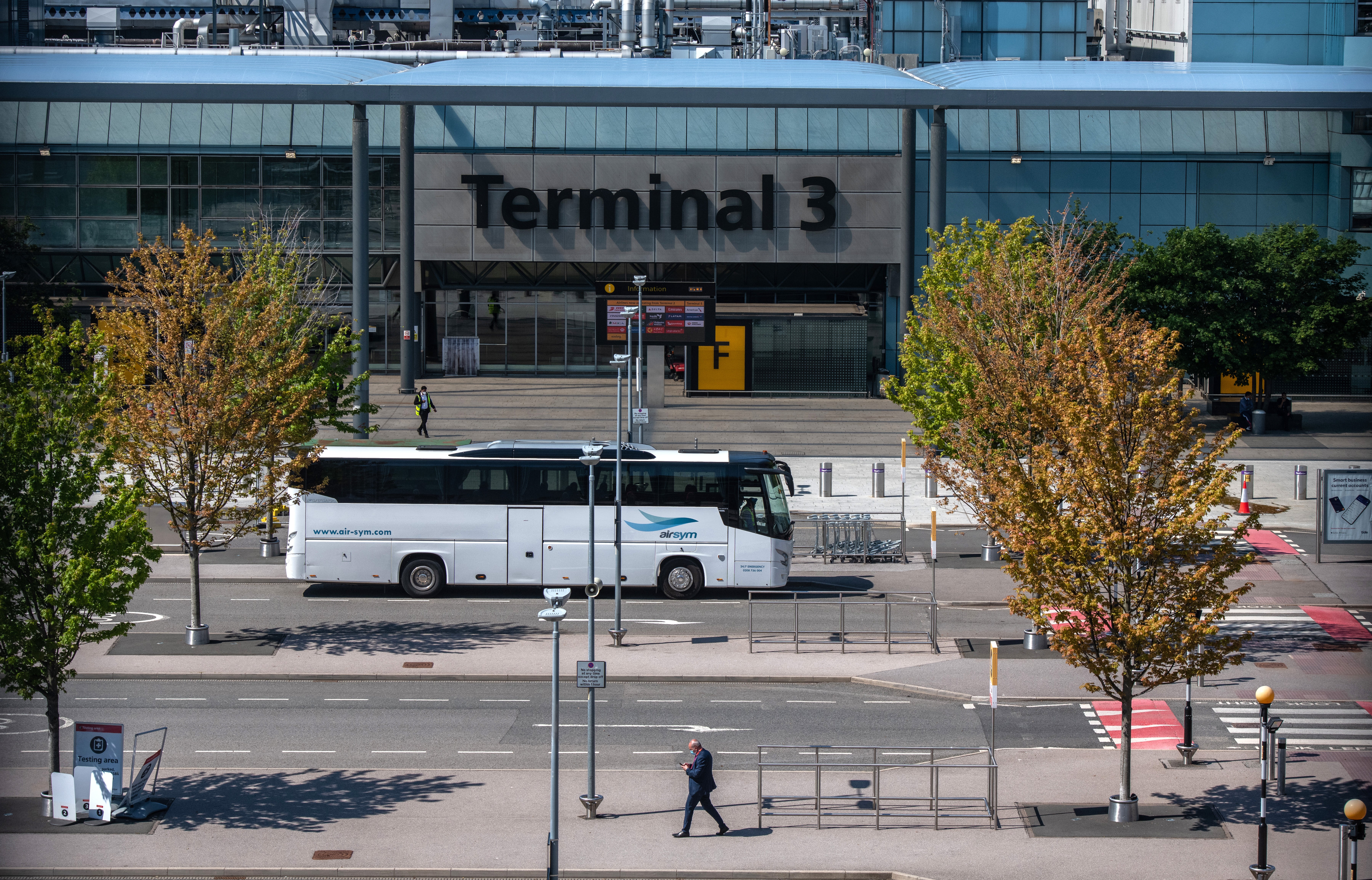 A bus used to transport red list arriving airline passengers passes the Terminal 3 building at Heathrow Airport