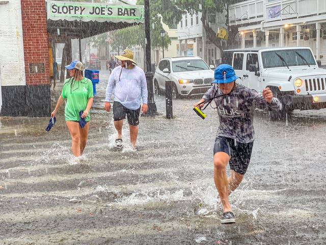 <p>Pedestrians dash across the intersection of Greene and Duval streets as heavy winds and rain associated with Tropical Storm Elsa passes Key West, Florida</p>